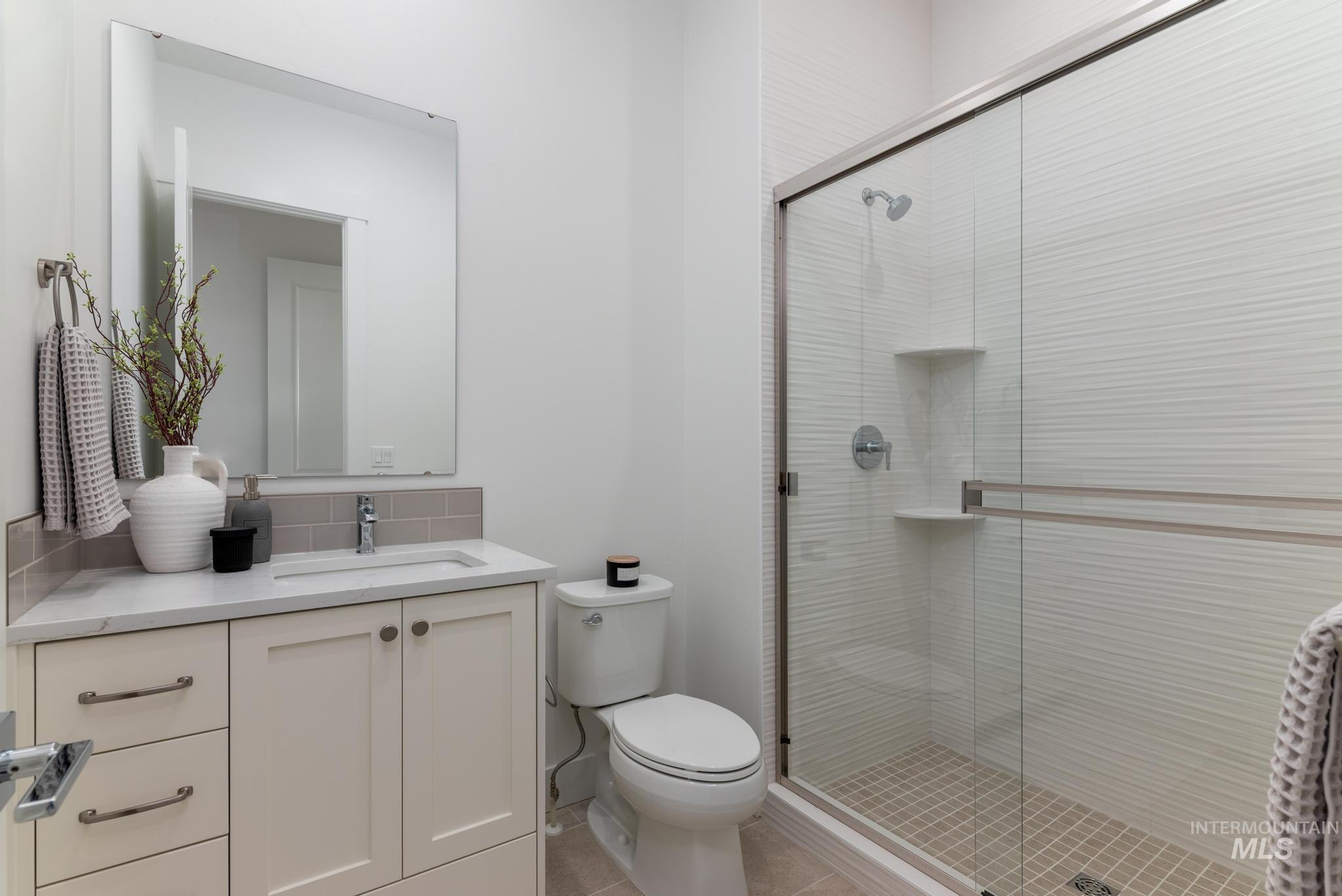 Full bathroom featuring vanity, a shower stall, and light tile patterned flooring
