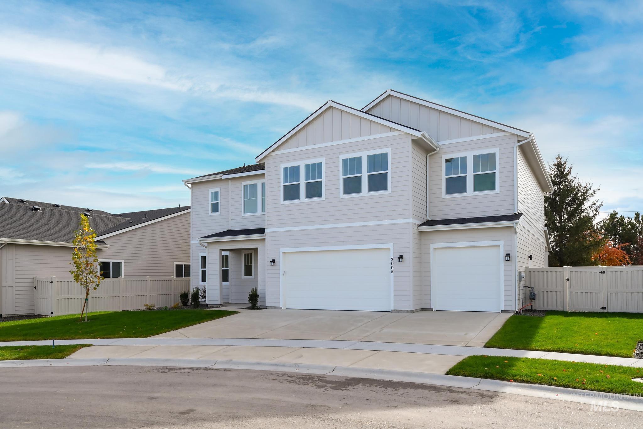 View of front of house with concrete driveway, an attached garage, board and batten siding, and a gate
