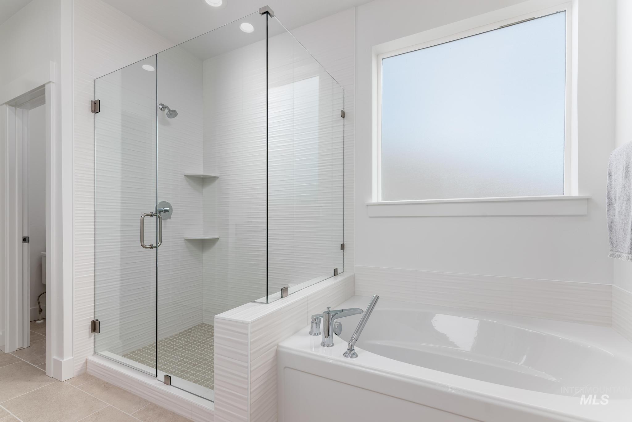 Bathroom featuring a bath, a stall shower, light tile patterned floors, and recessed lighting