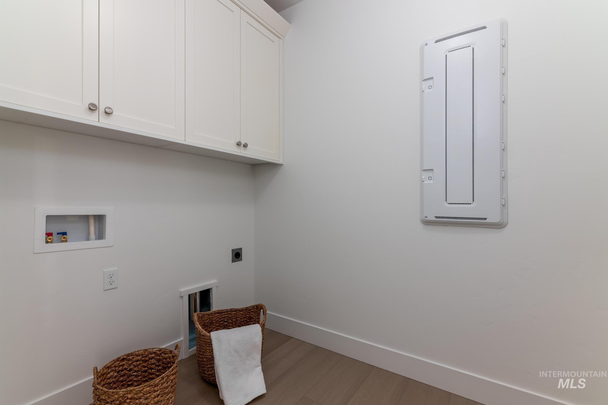 Laundry room featuring washer hookup, cabinet space, hookup for an electric dryer, light wood finished floors, and electric panel