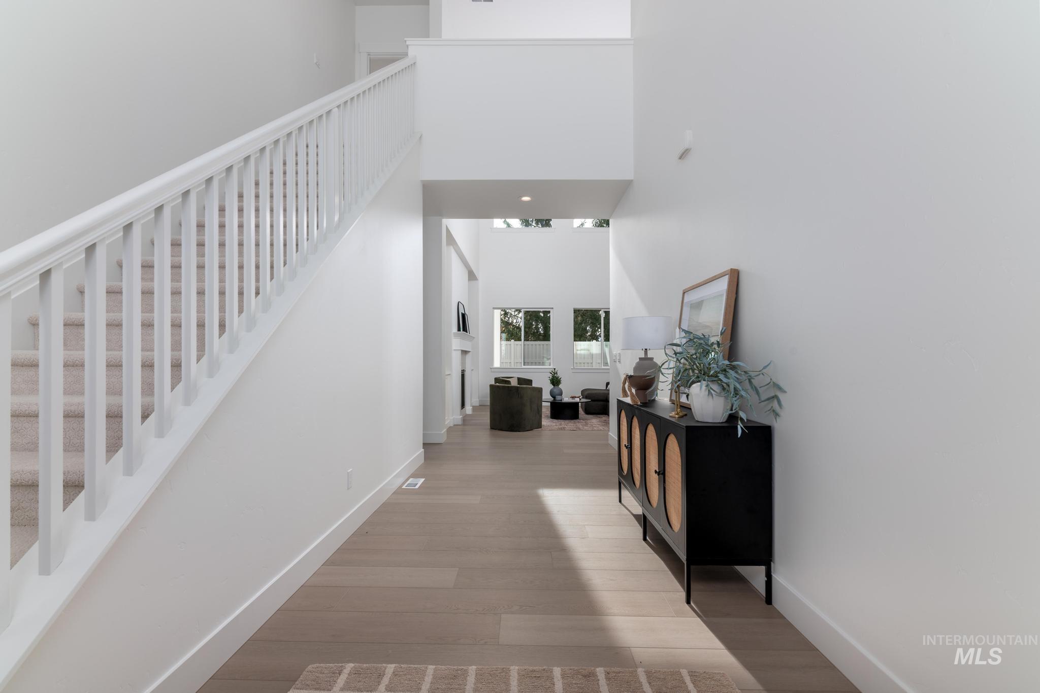 Corridor featuring a towering ceiling, light wood-type flooring, and stairs