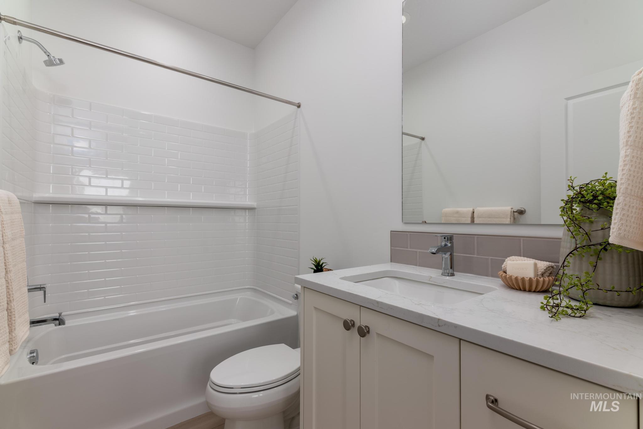 Bathroom with vanity, shower / tub combination, and decorative backsplash