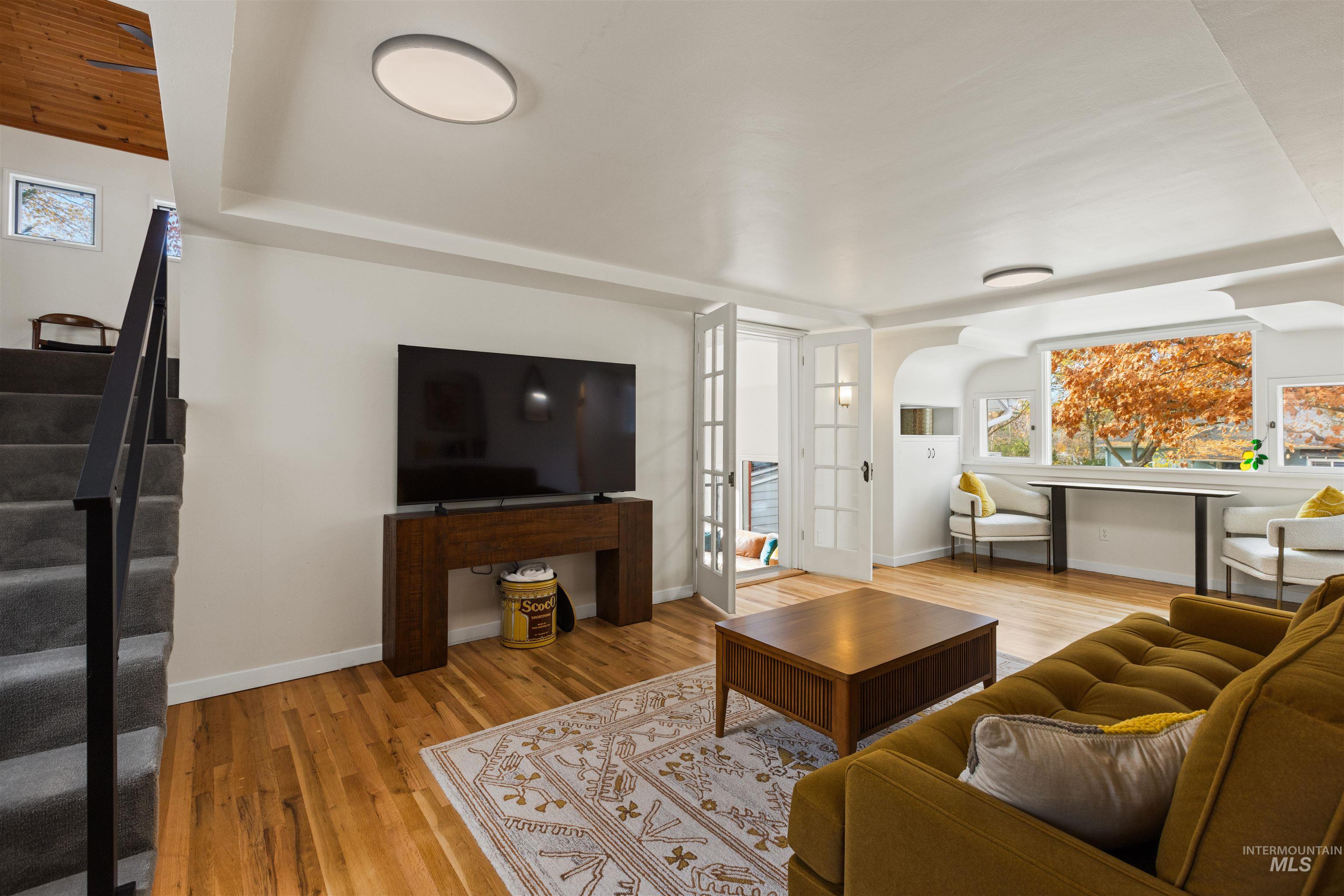 Living area with plenty of natural light, light wood-style floors, and stairs