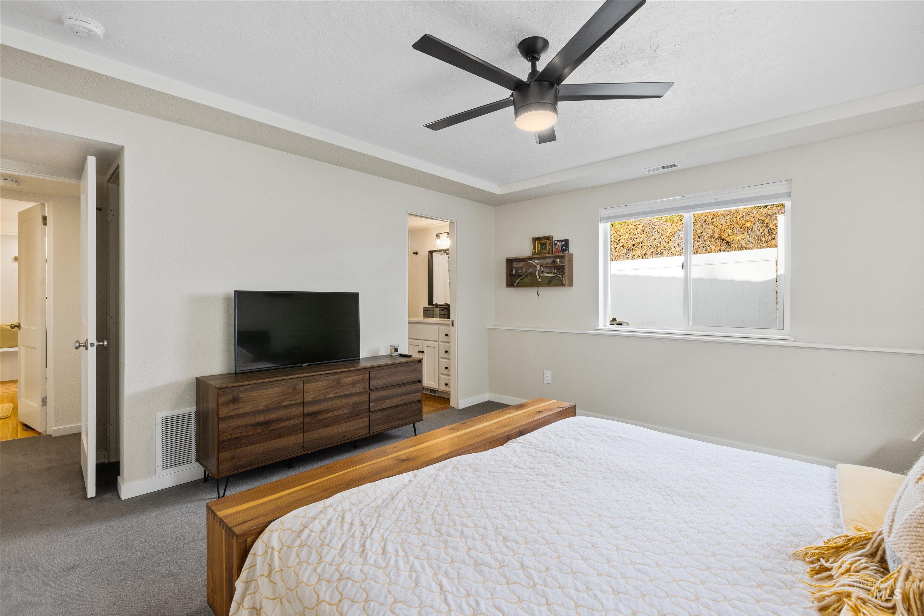 Bedroom featuring ensuite bath, ceiling fan, and carpet floors