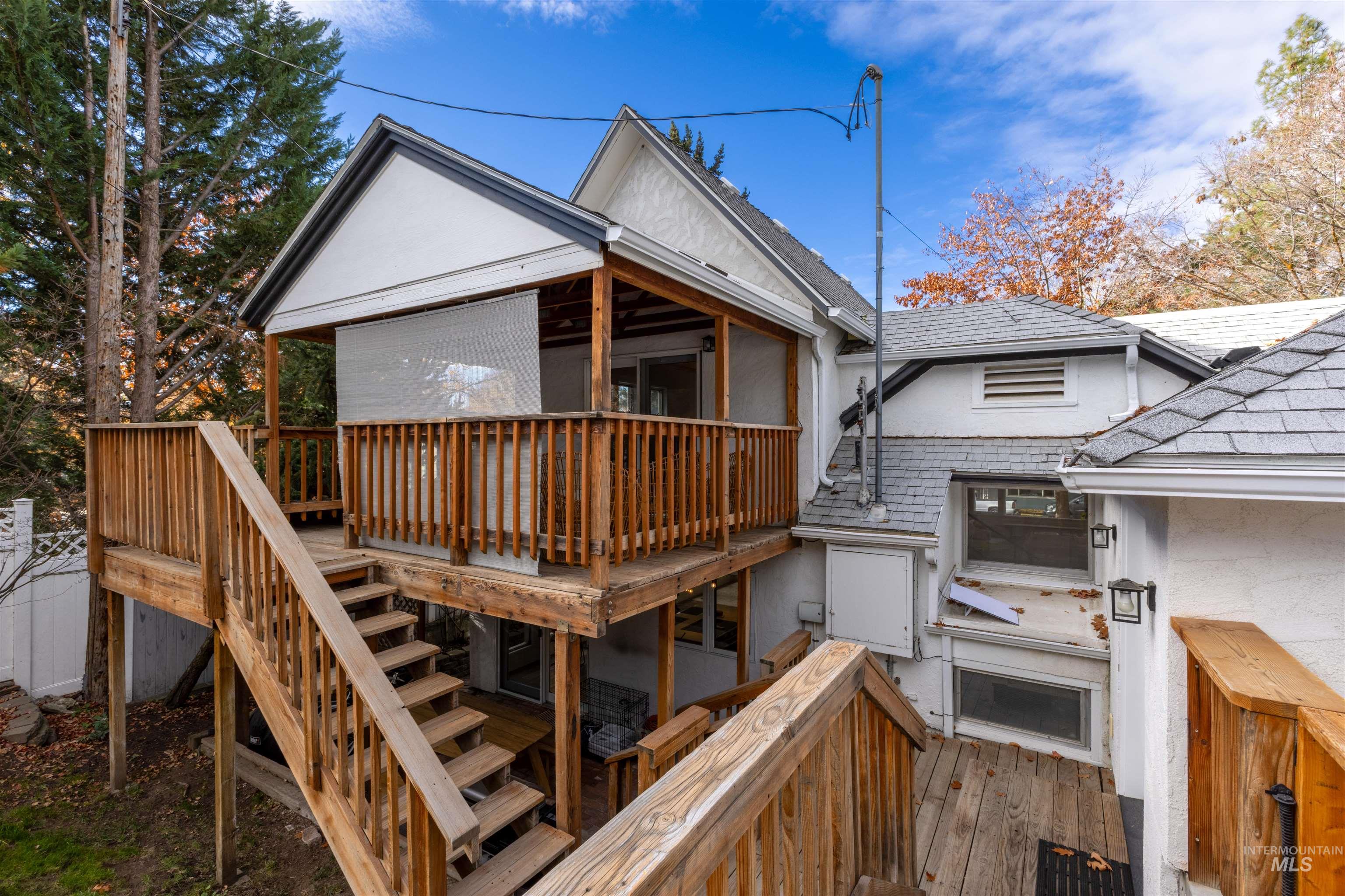Back of house with stairway, a wooden deck, stucco siding, and roof with shingles