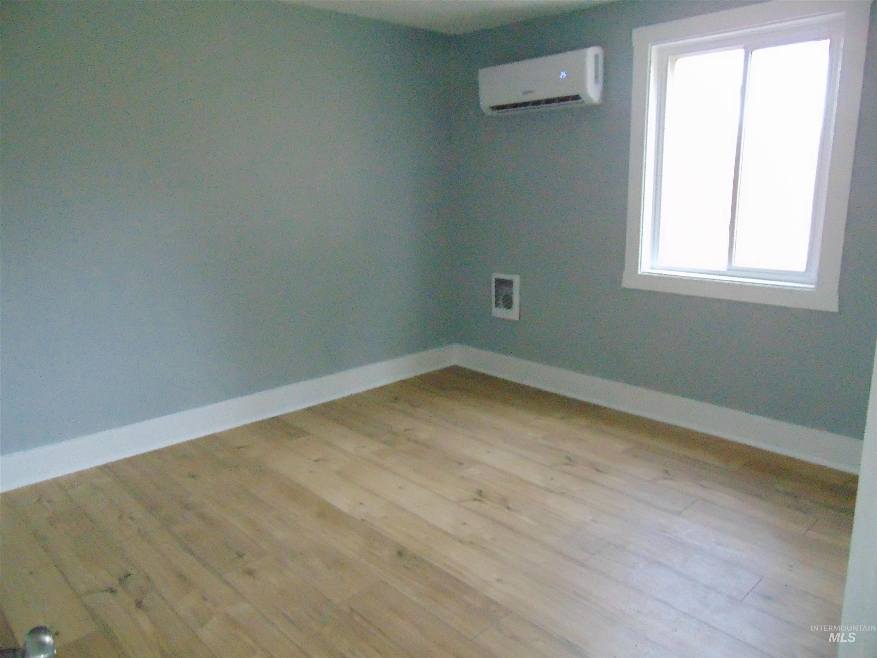 Unfurnished room with a wall mounted AC and light wood-style flooring
