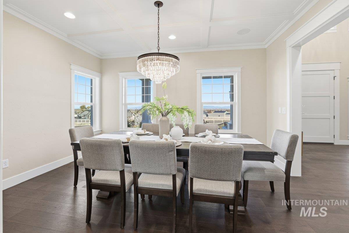 Dining area with healthy amount of natural light, recessed lighting, dark wood-style flooring, coffered ceiling, and a chandelier