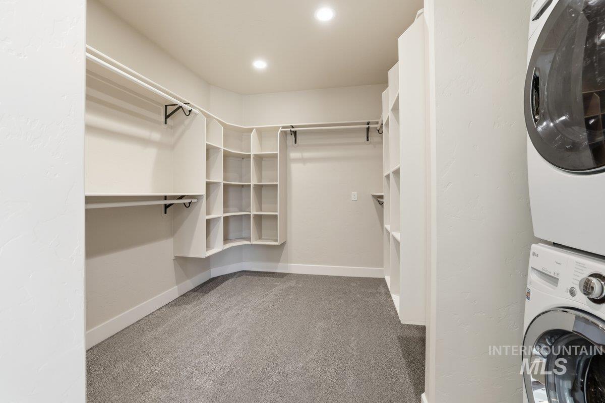 Spacious closet featuring light carpet and estacked washer and dryer