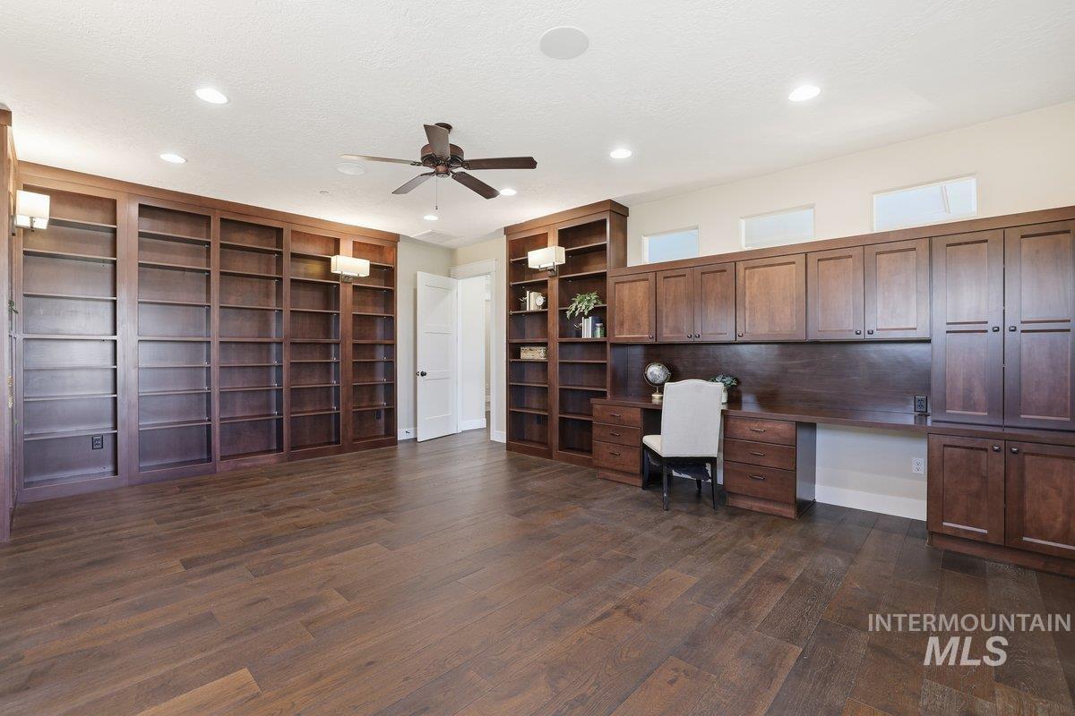 Library featuring ceiling fan, built in desk, dark wood finished floors, recessed lighting, and a textured ceiling, built in shelving.