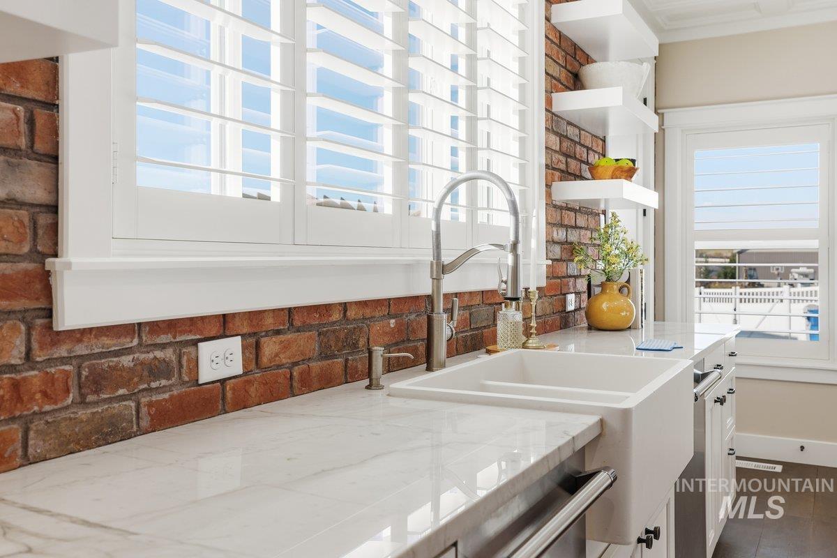 Kitchen view of open shelves, white cabinets, and light stone countertops