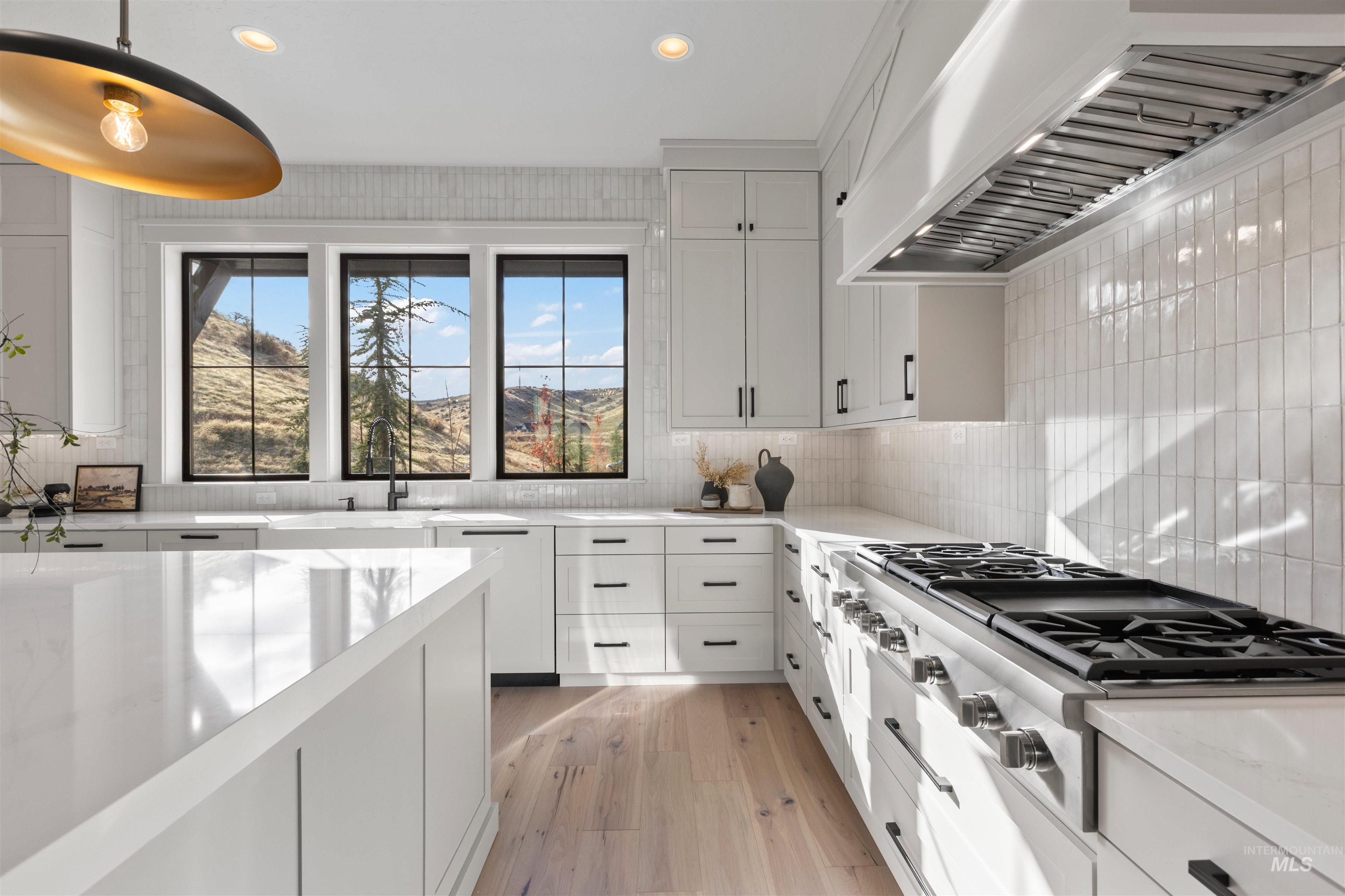 Kitchen with white cabinetry, wall chimney range hood, recessed lighting, stainless steel gas cooktop, and light wood-type flooring