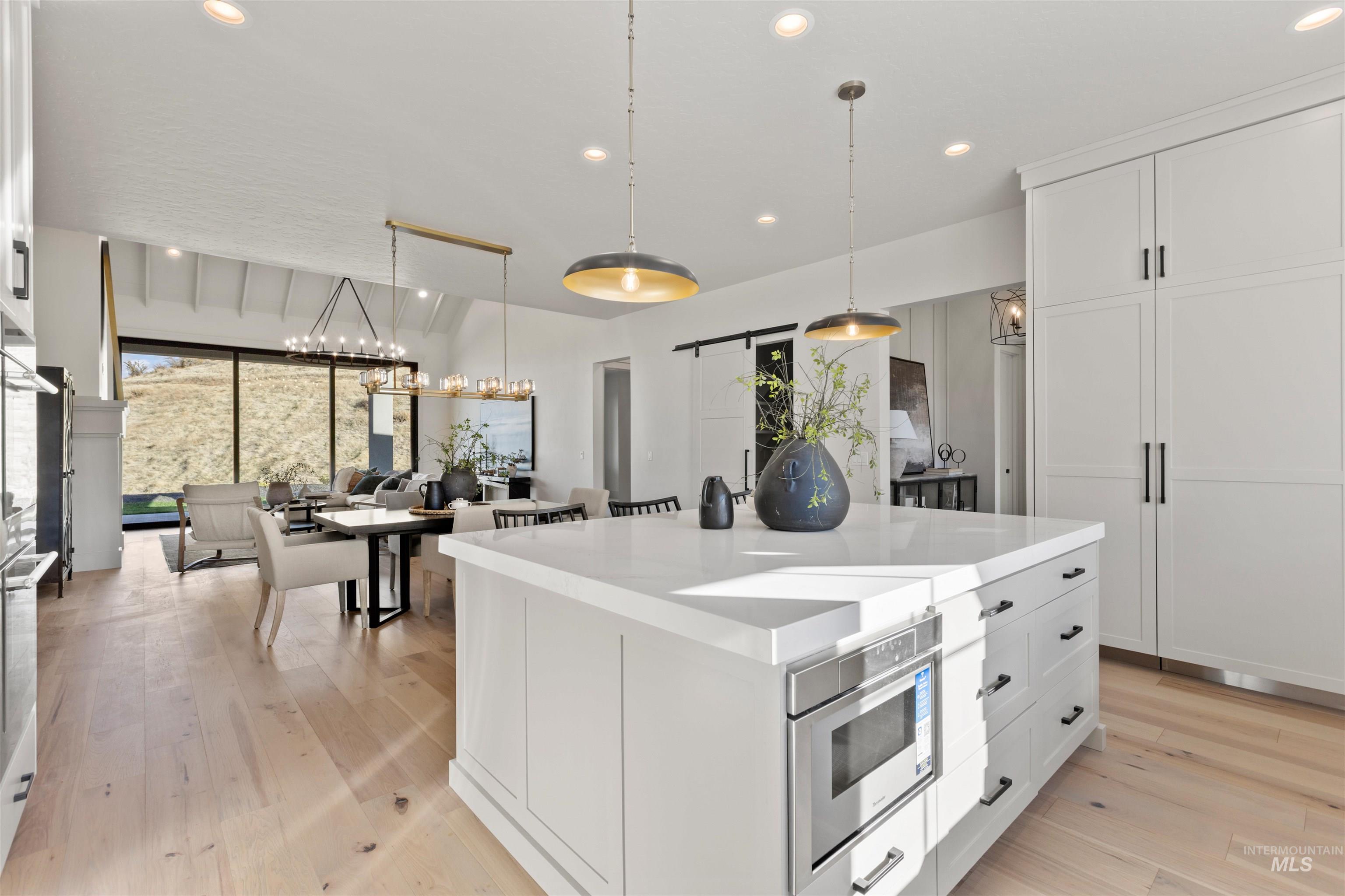 Kitchen featuring a barn door, white cabinetry, a kitchen island, recessed lighting, and light wood-style floors