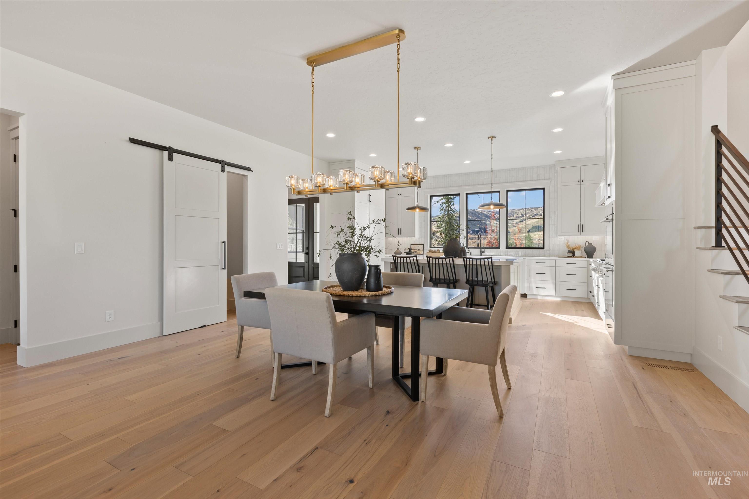 Dining room with a barn door, light wood finished floors, and recessed lighting