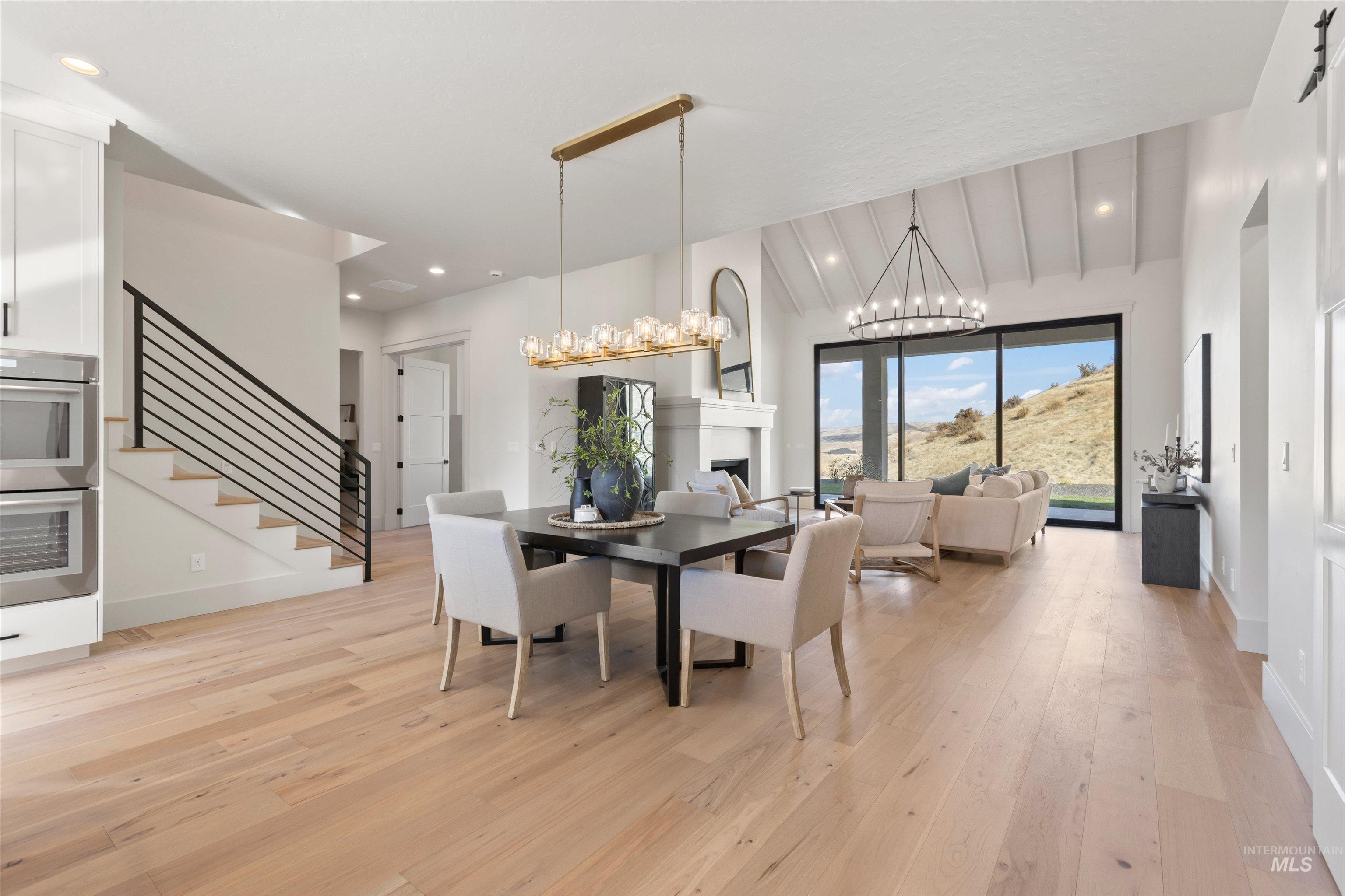 Dining area featuring light wood-style floors, stairway, a fireplace, recessed lighting, and a chandelier