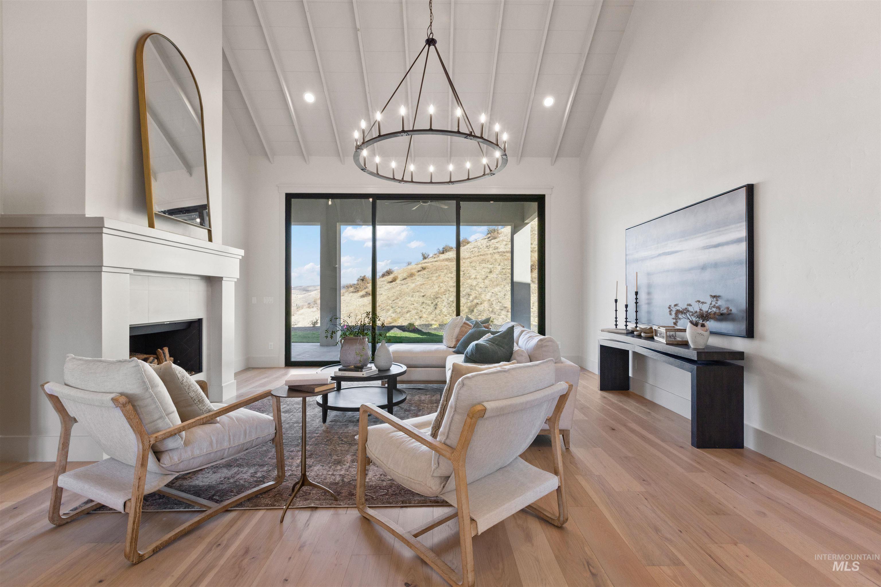 Living room featuring light wood-style floors, a fireplace, high vaulted ceiling, recessed lighting, and a chandelier