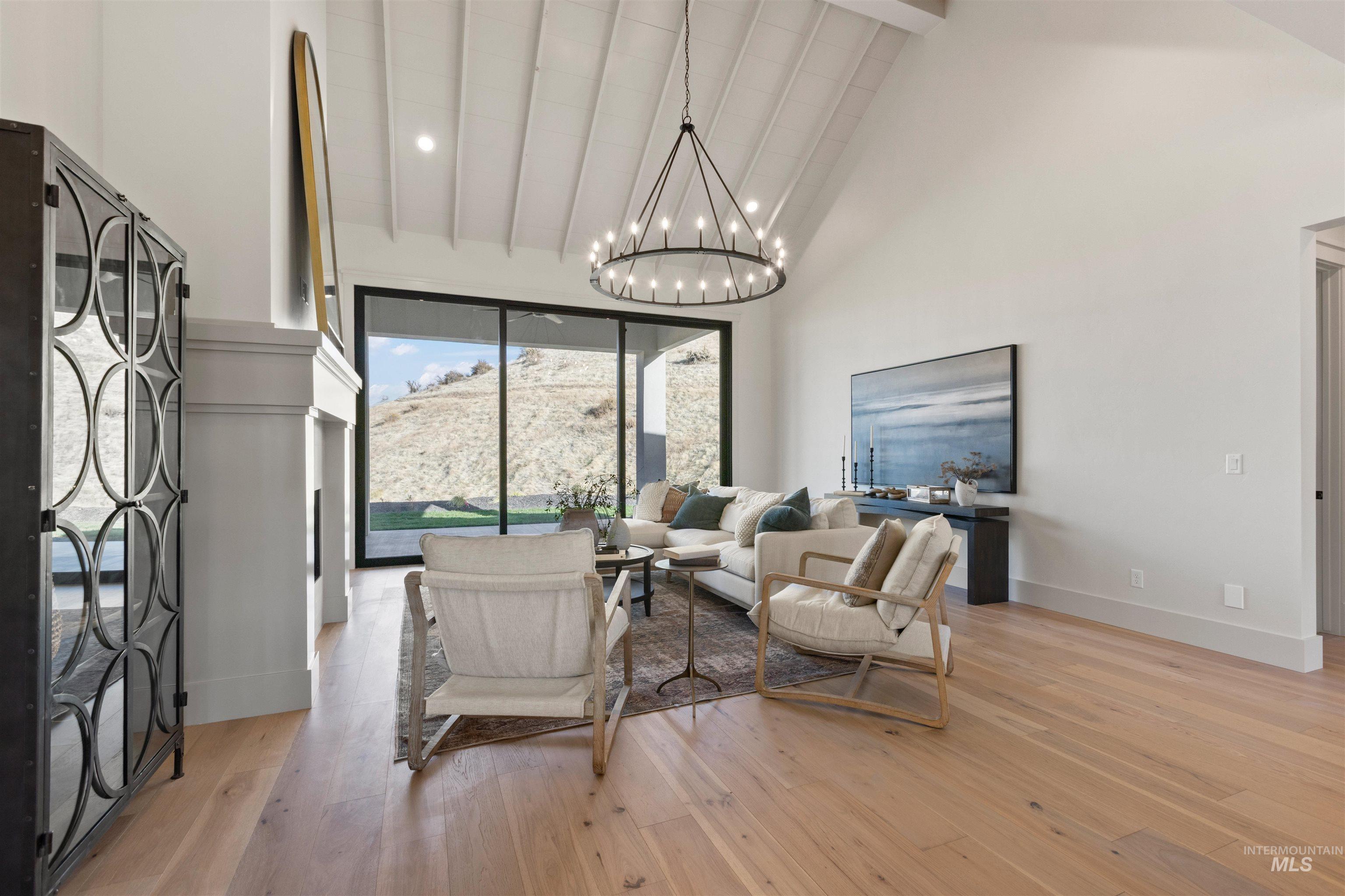 Living area with high vaulted ceiling, light wood-style flooring, a chandelier, beam ceiling, and recessed lighting