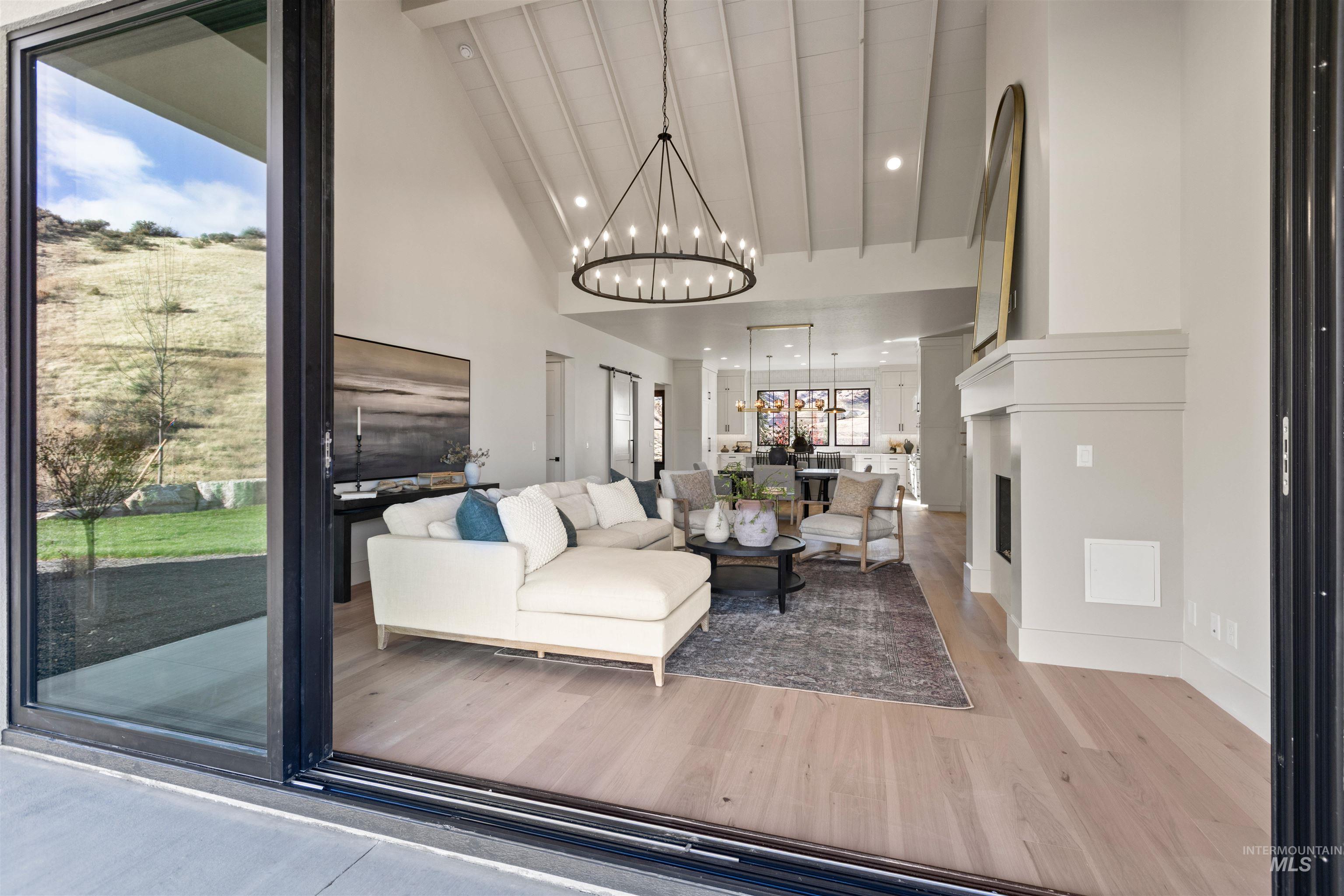 Living room featuring a fireplace, wood finished floors, a chandelier, high vaulted ceiling, and recessed lighting