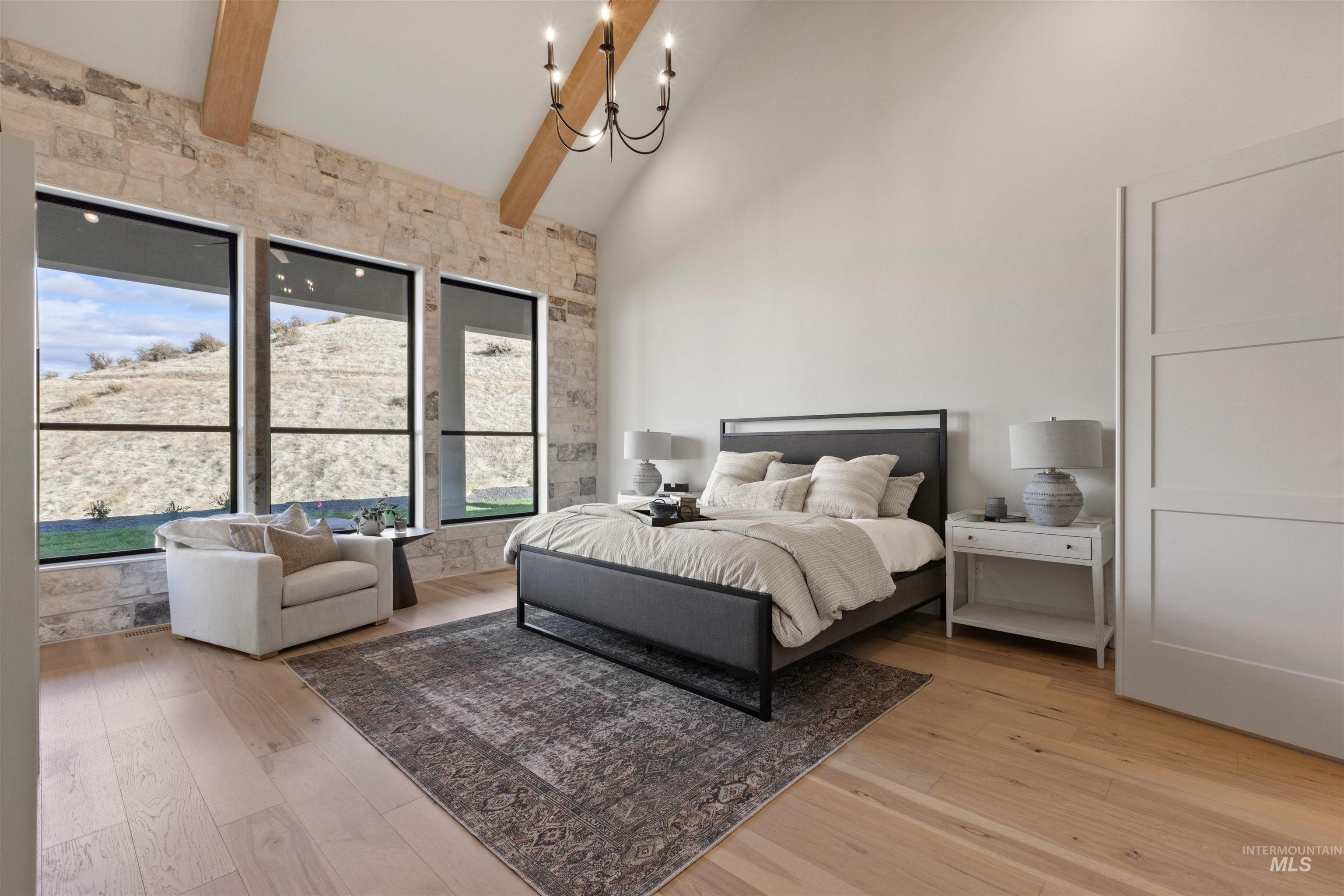 Bedroom with beamed ceiling, a chandelier, high vaulted ceiling, and light wood-style floors