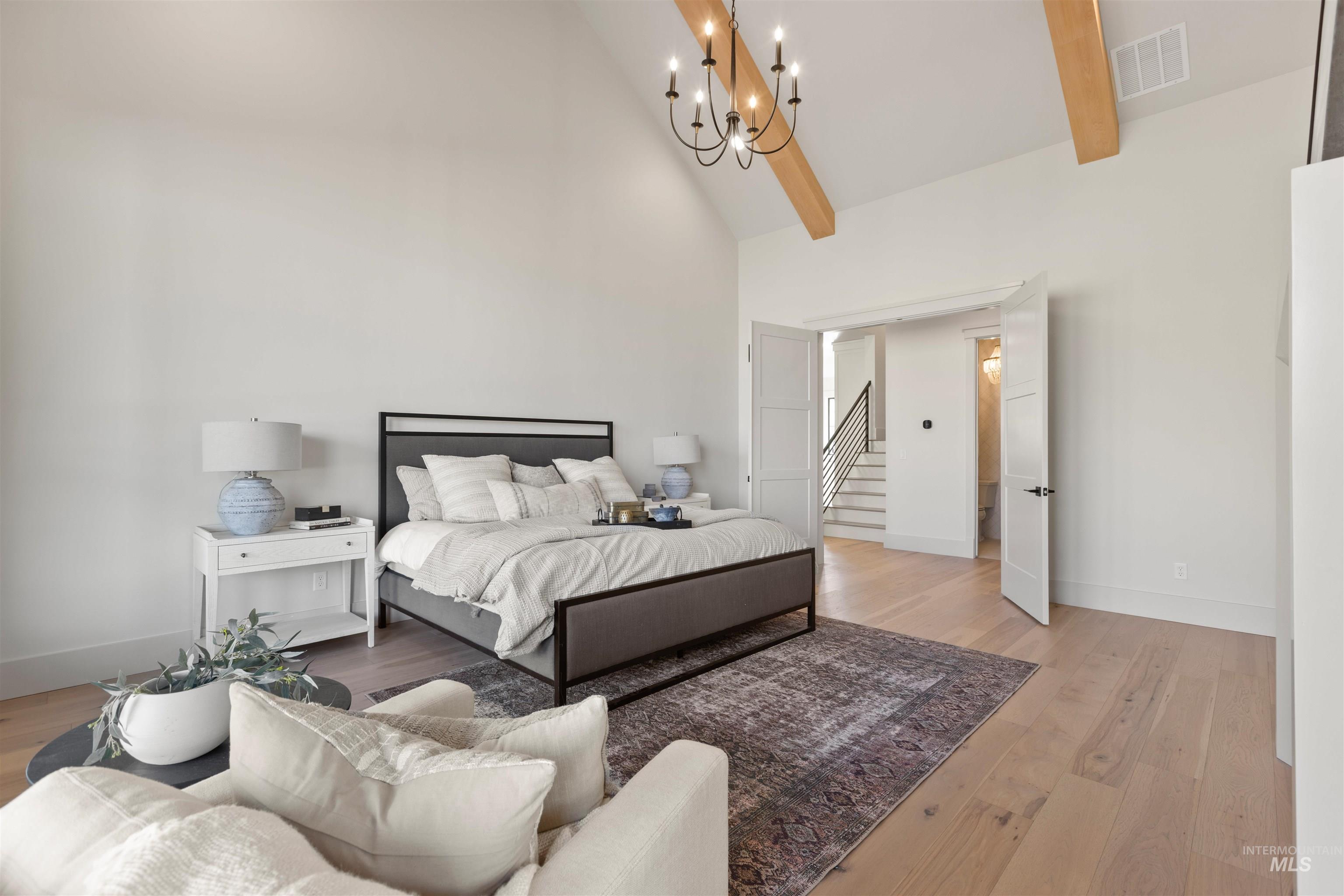 Bedroom with high vaulted ceiling, a chandelier, light wood finished floors, and beam ceiling