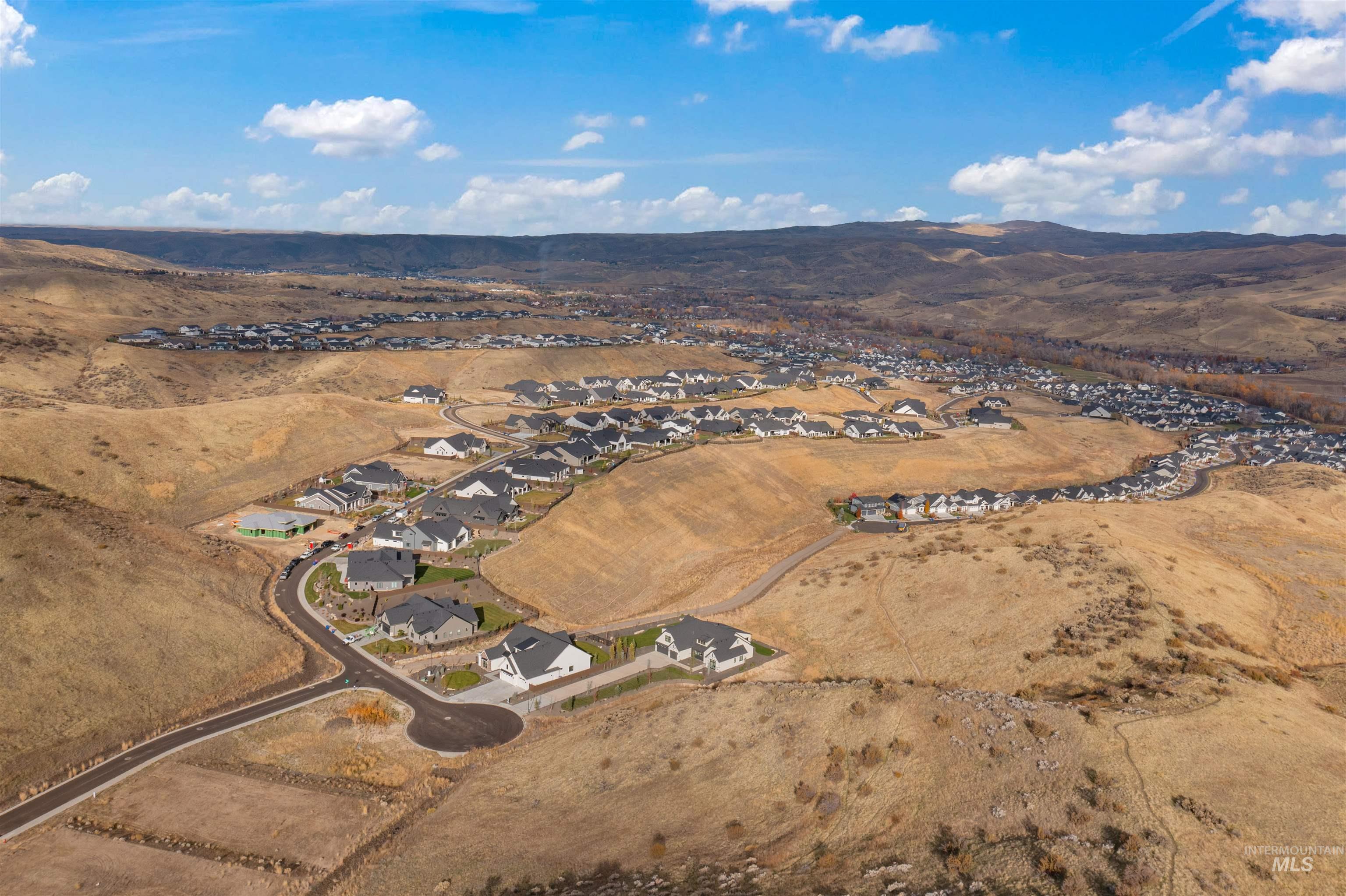Aerial view of property's location with nearby suburban area and a mountainous background