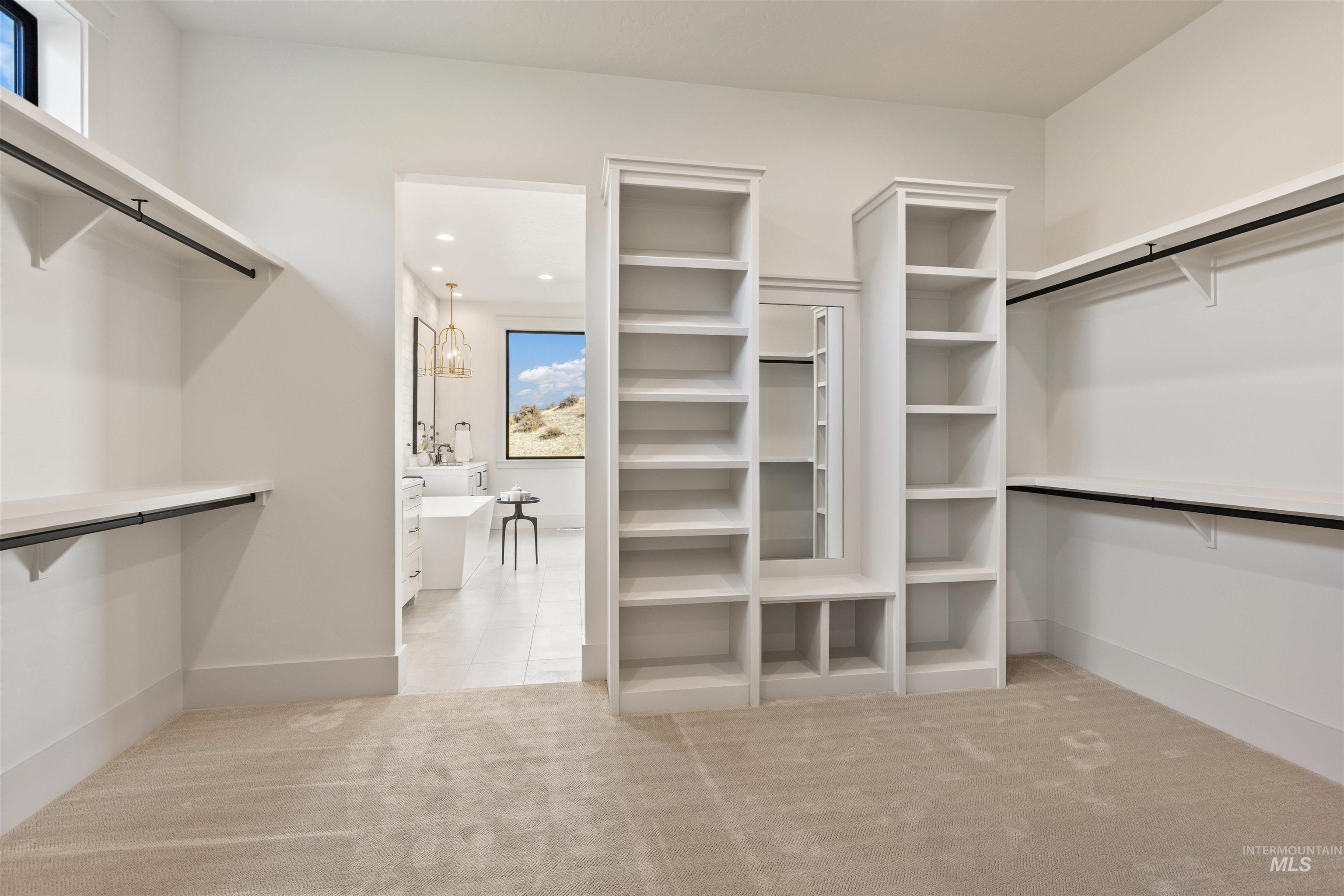 Walk in closet with light colored carpet, light tile patterned floors, and a chandelier