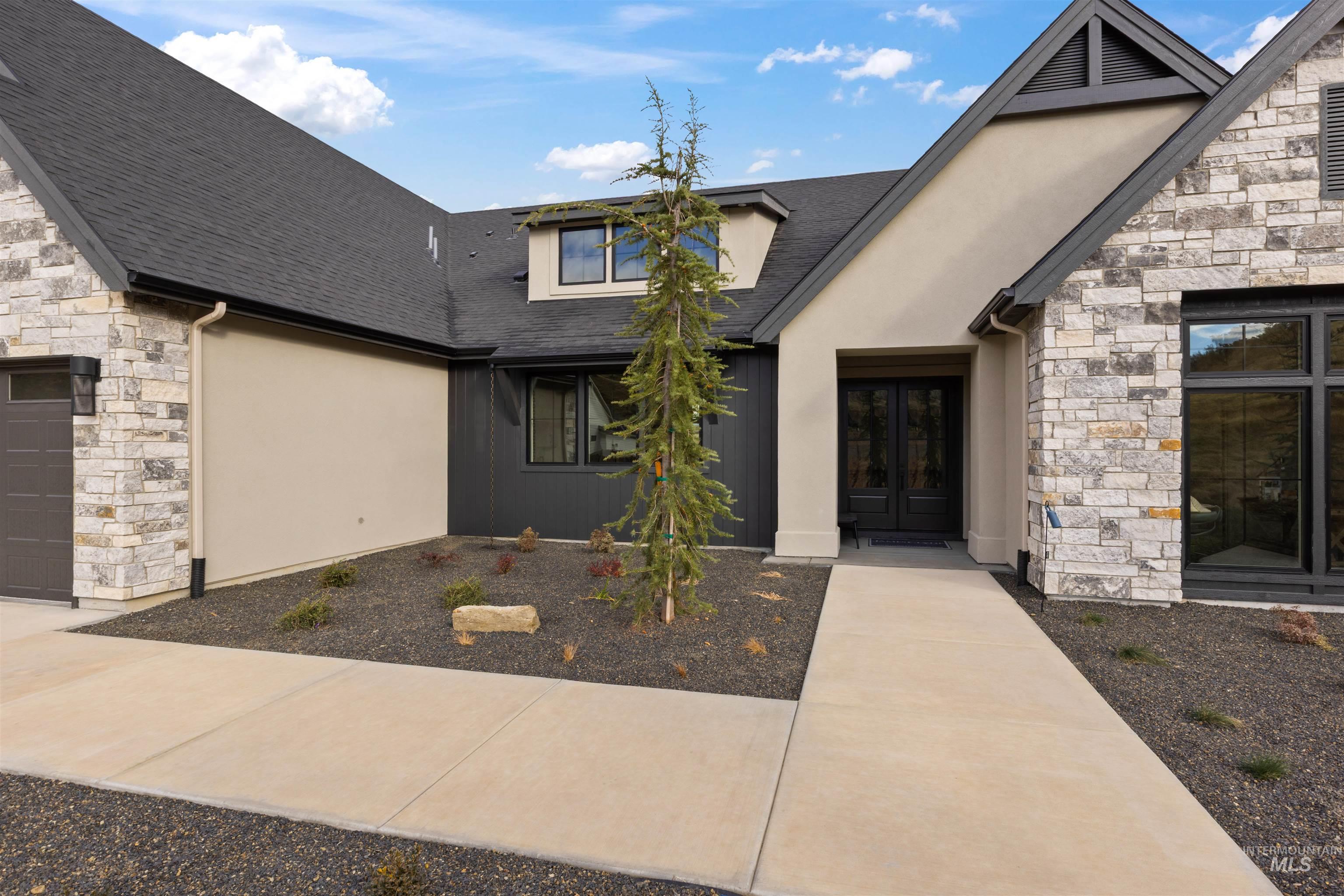 Property entrance with stone siding, roof with shingles, stucco siding, and a garage