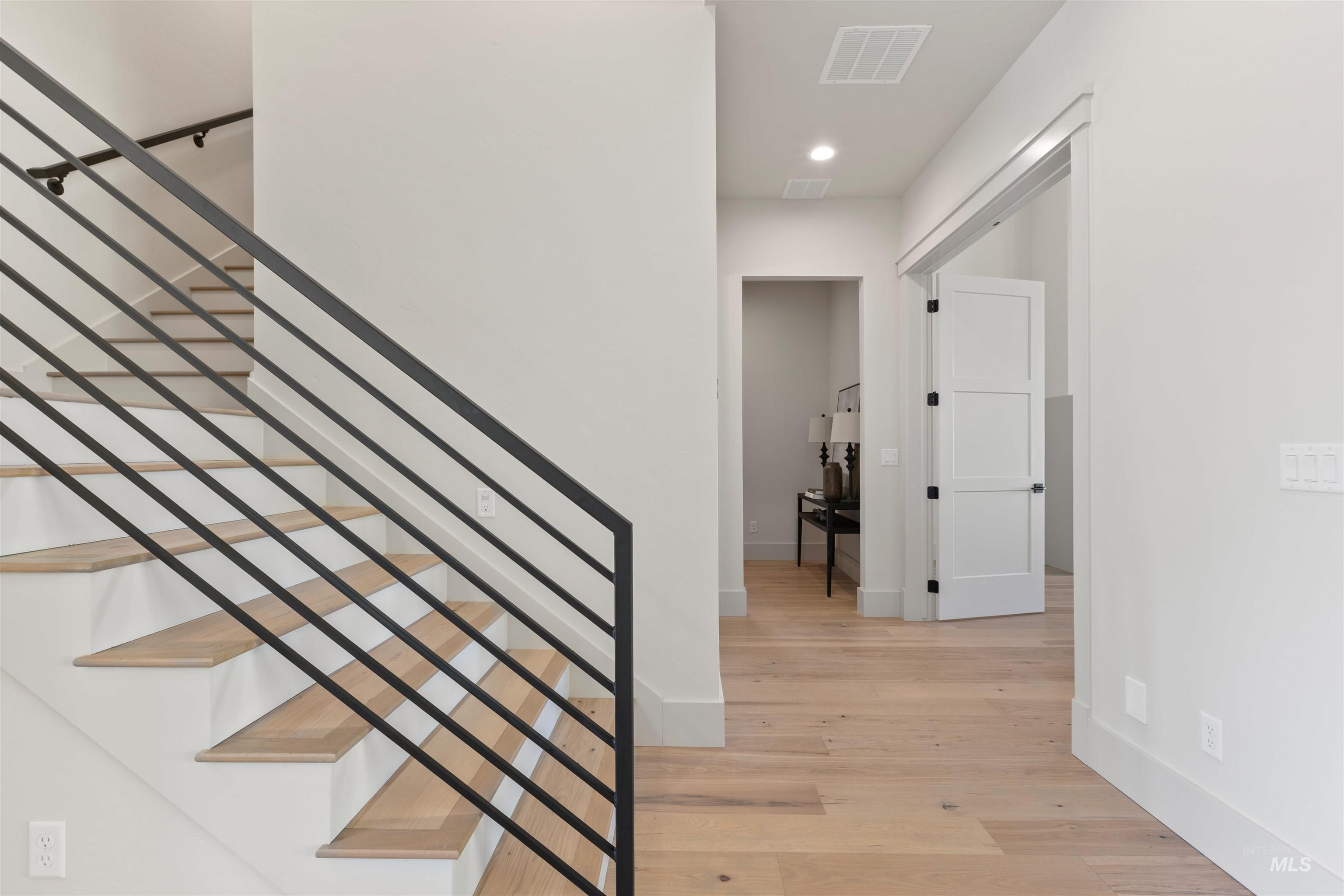 Stairs with wood finished floors and recessed lighting