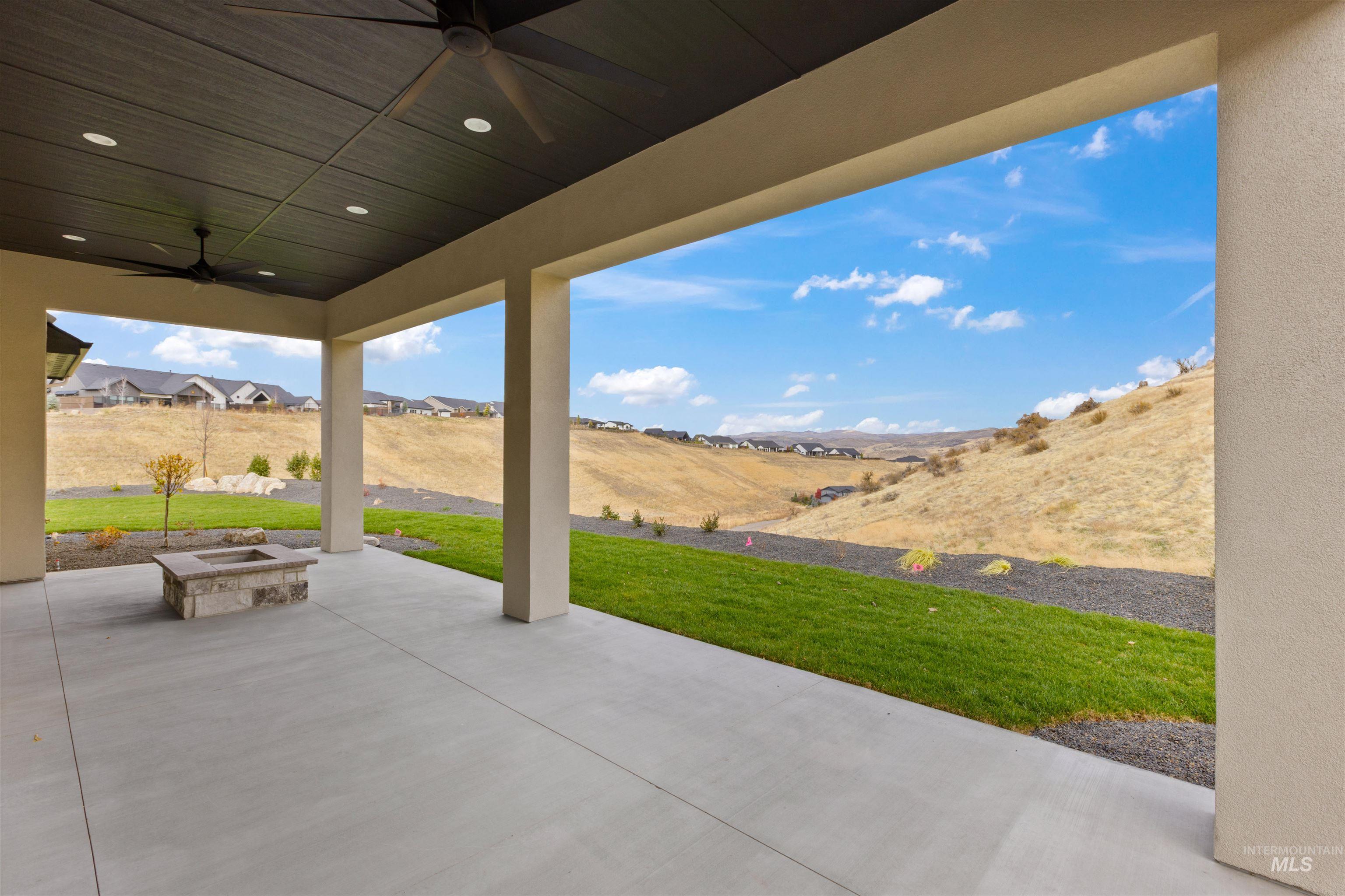 View of patio with ceiling fan, a fire pit, and a residential view