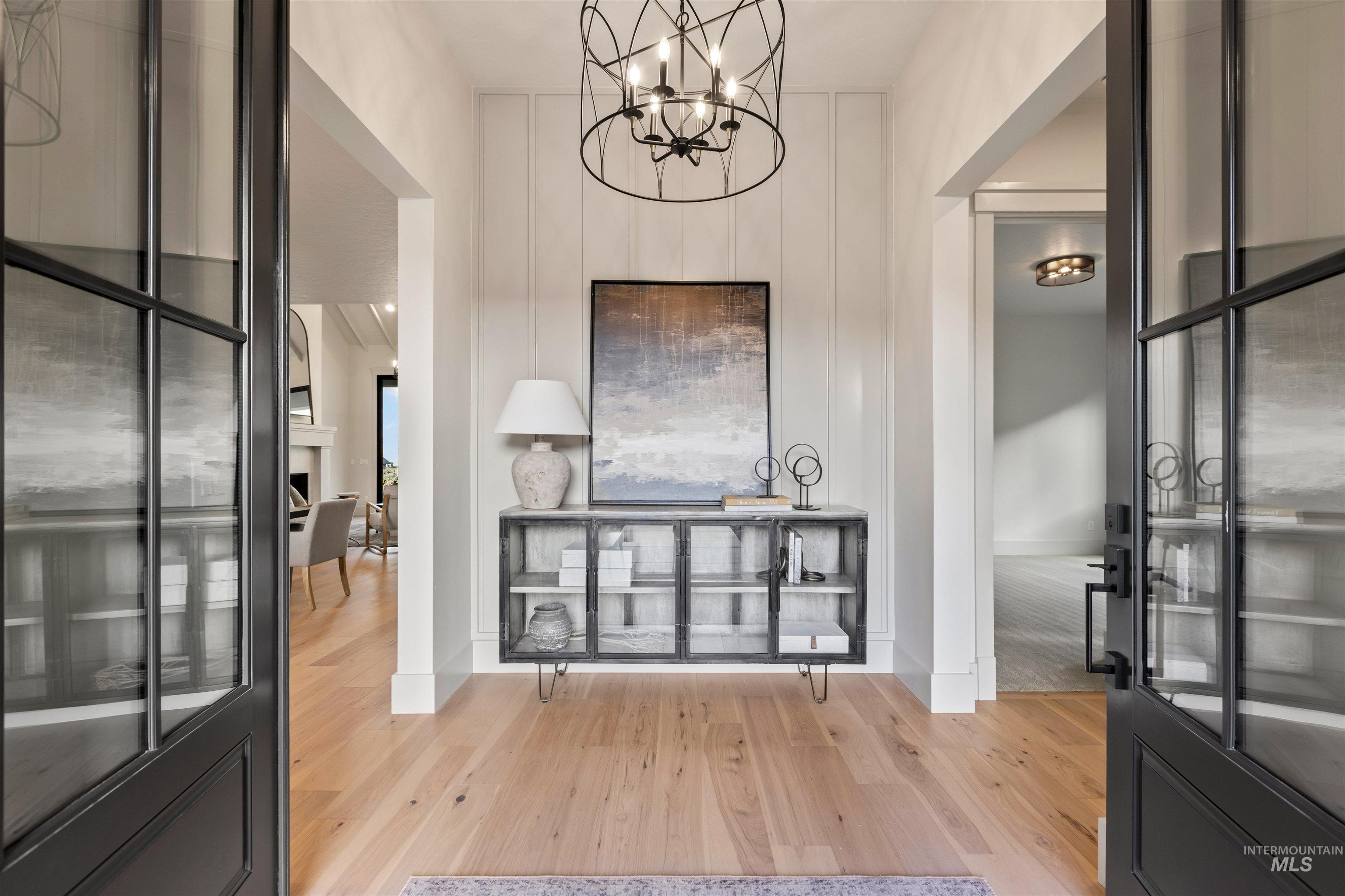 Entryway with light wood finished floors and a chandelier