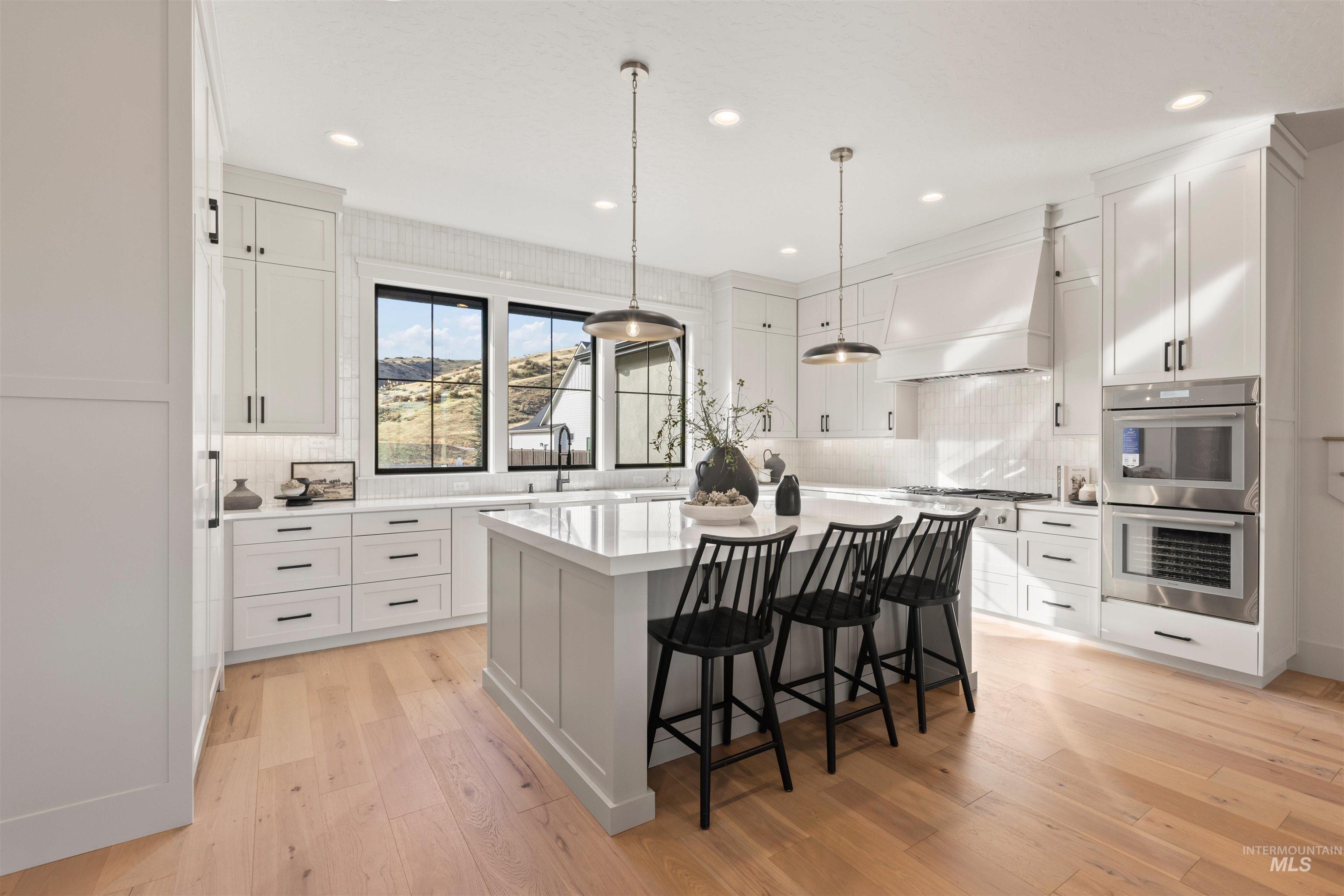 Kitchen featuring a kitchen island, a breakfast bar area, pendant lighting, appliances with stainless steel finishes, and light wood finished floors