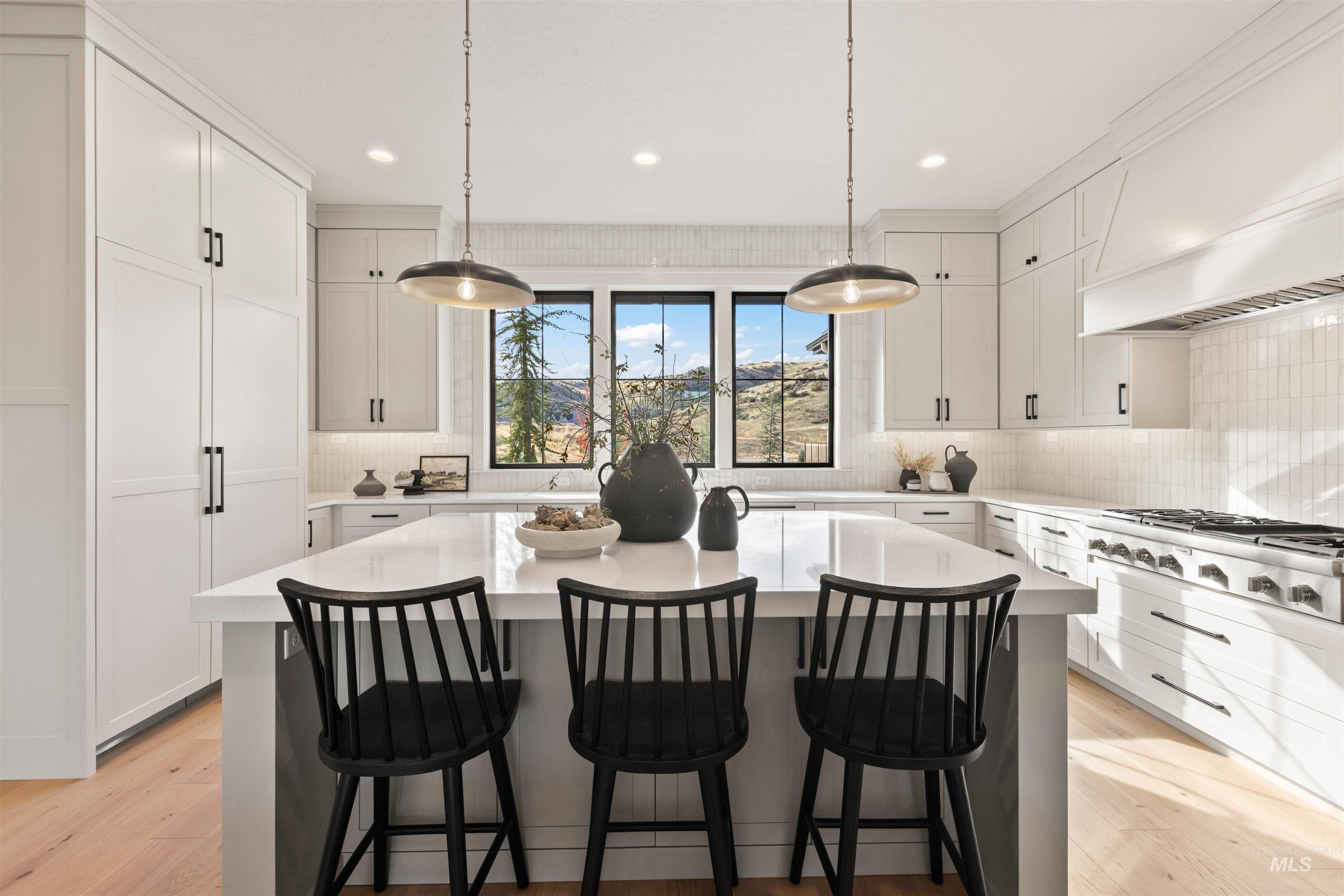 Kitchen featuring a kitchen bar, hanging light fixtures, white cabinetry, stainless steel gas stovetop, and recessed lighting