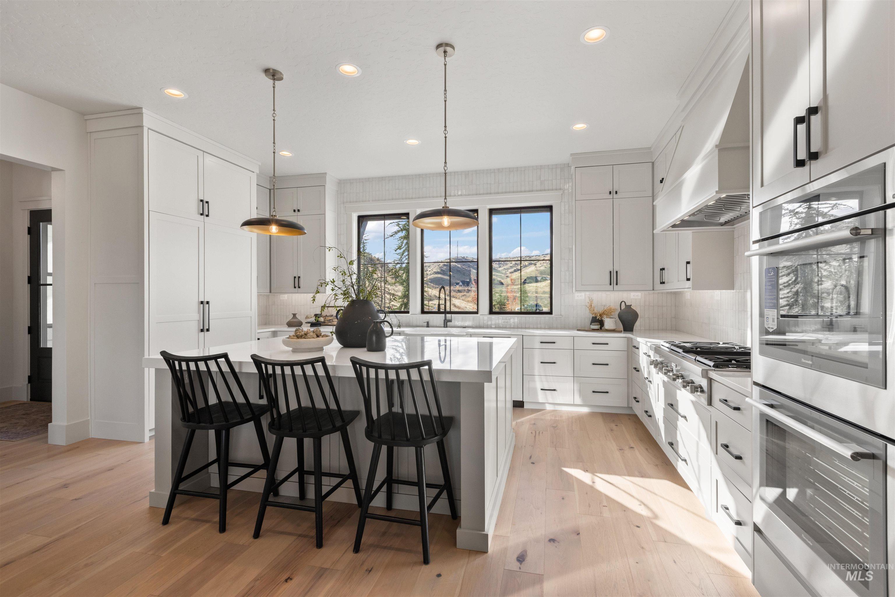 Kitchen with appliances with stainless steel finishes, a kitchen bar, a kitchen island, backsplash, and light wood-style flooring