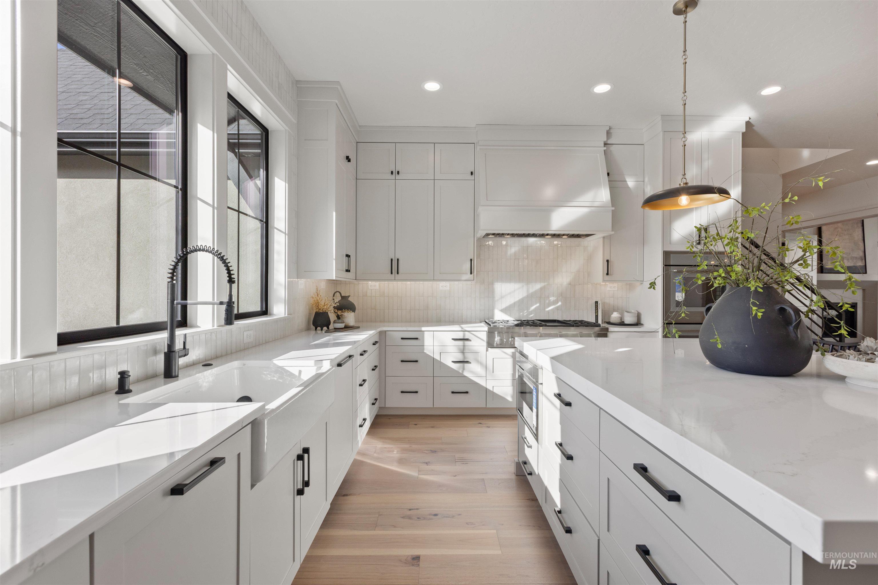 Kitchen with white cabinetry, decorative backsplash, pendant lighting, and recessed lighting