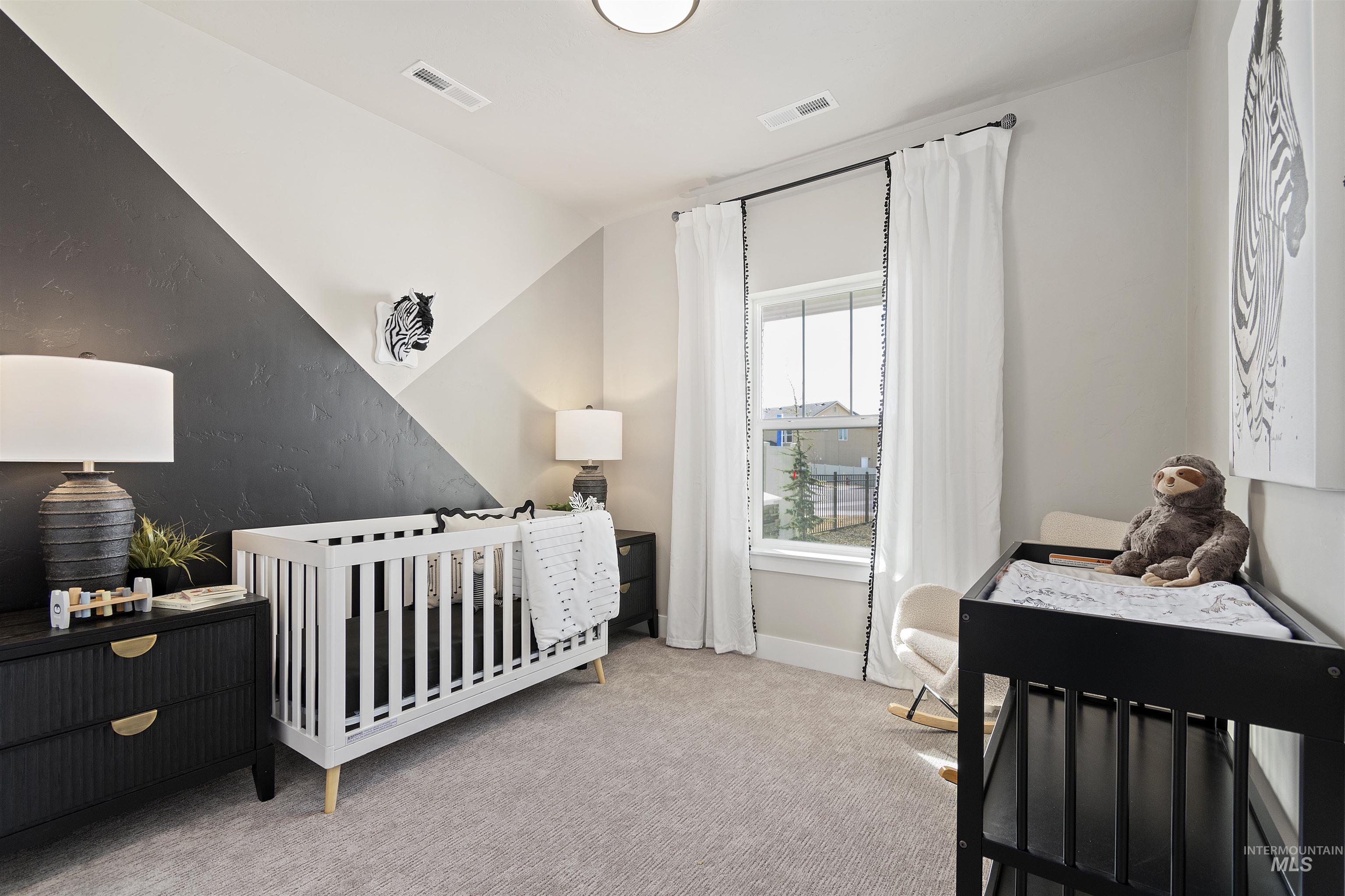 Bedroom featuring a nursery area, light colored carpet, and lofted ceiling