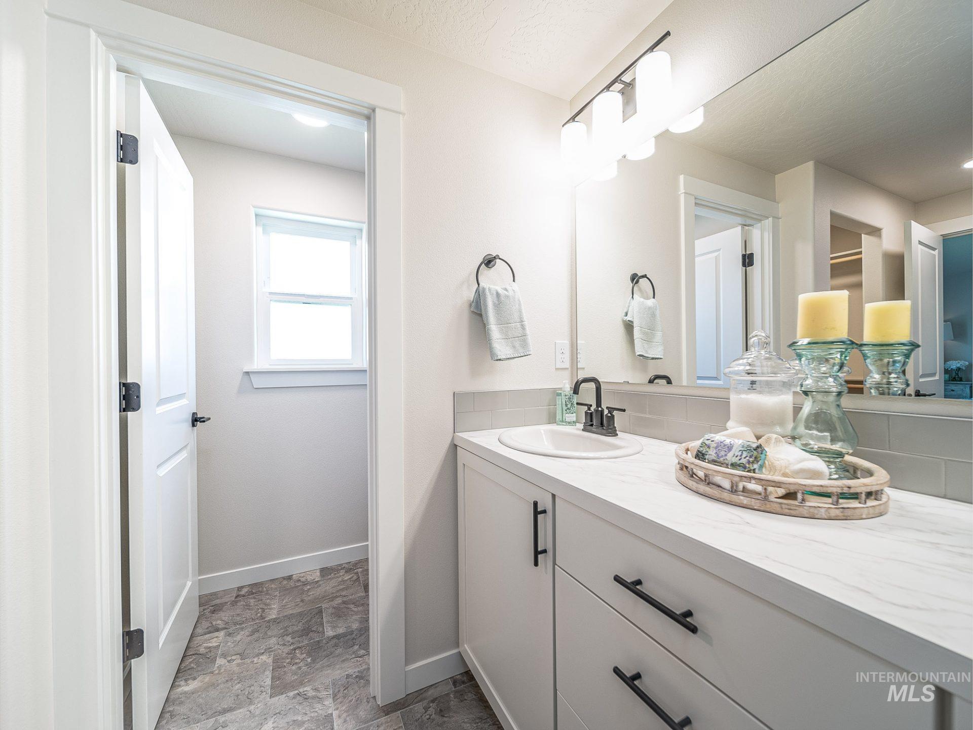 Bathroom with vanity, stone finish flooring, and decorative backsplash