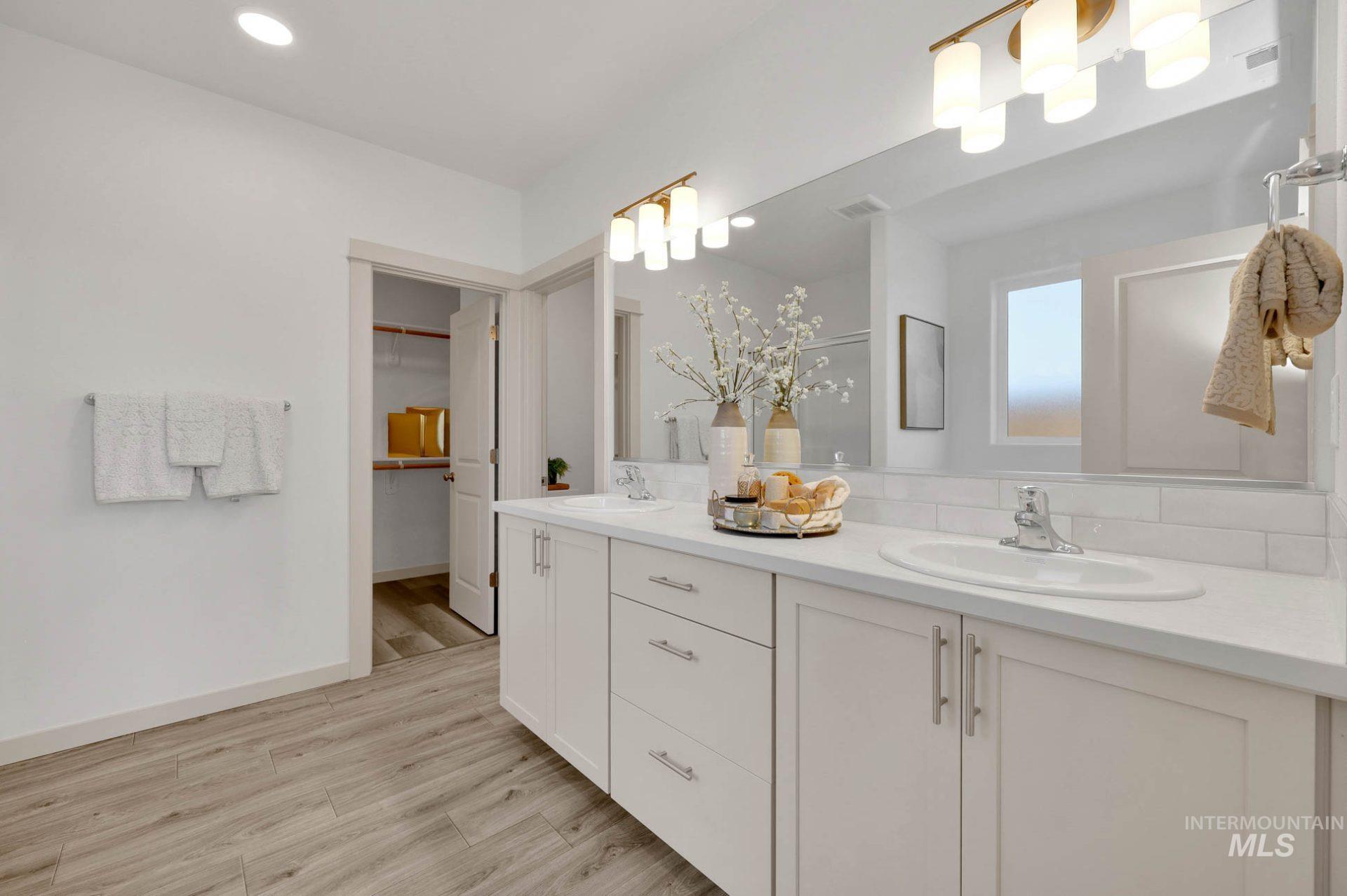 Bathroom featuring double vanity, light wood-style floors, a spacious closet, and recessed lighting