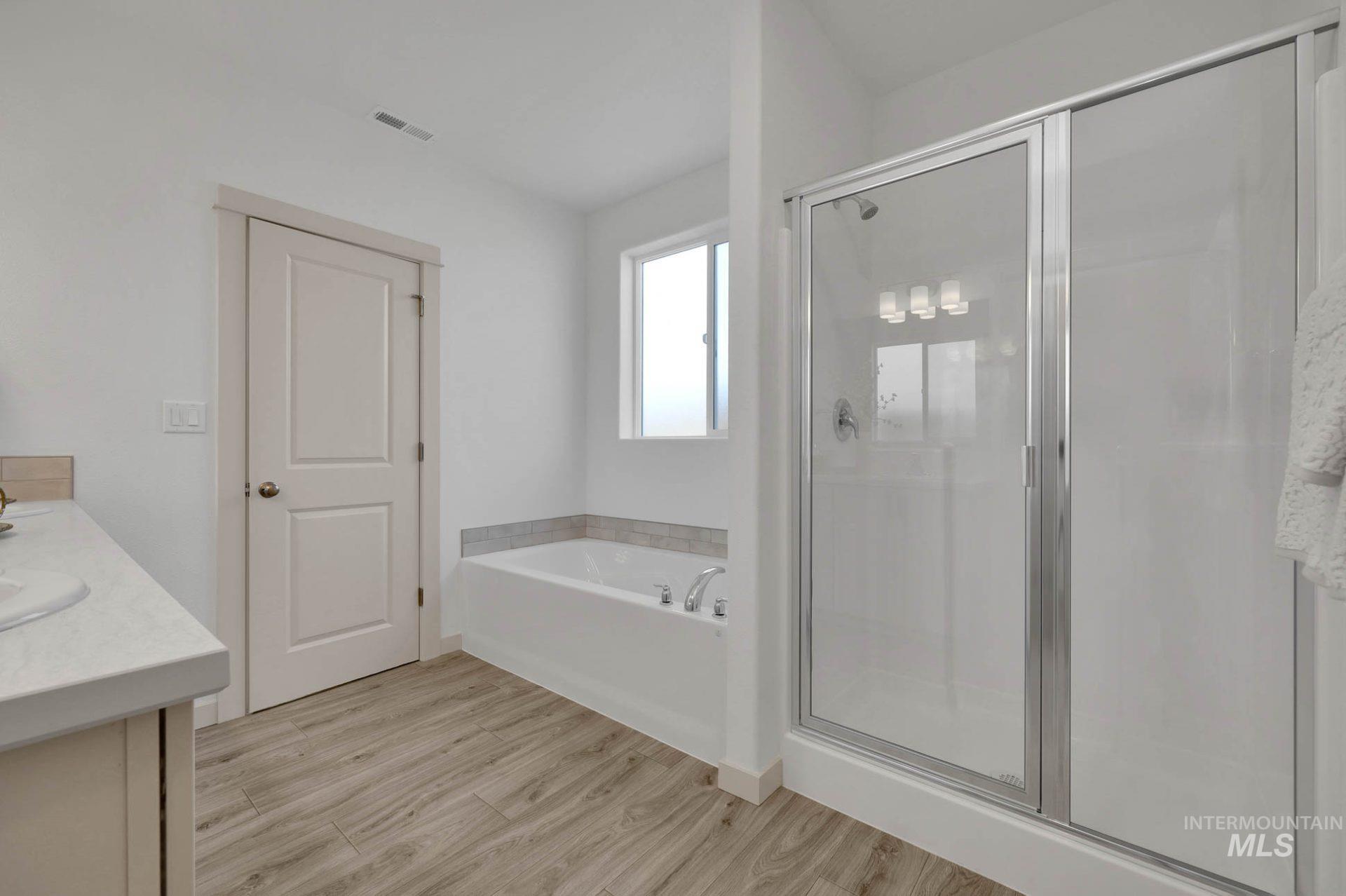 Full bathroom featuring vanity, a garden tub, light wood-style flooring, and a stall shower