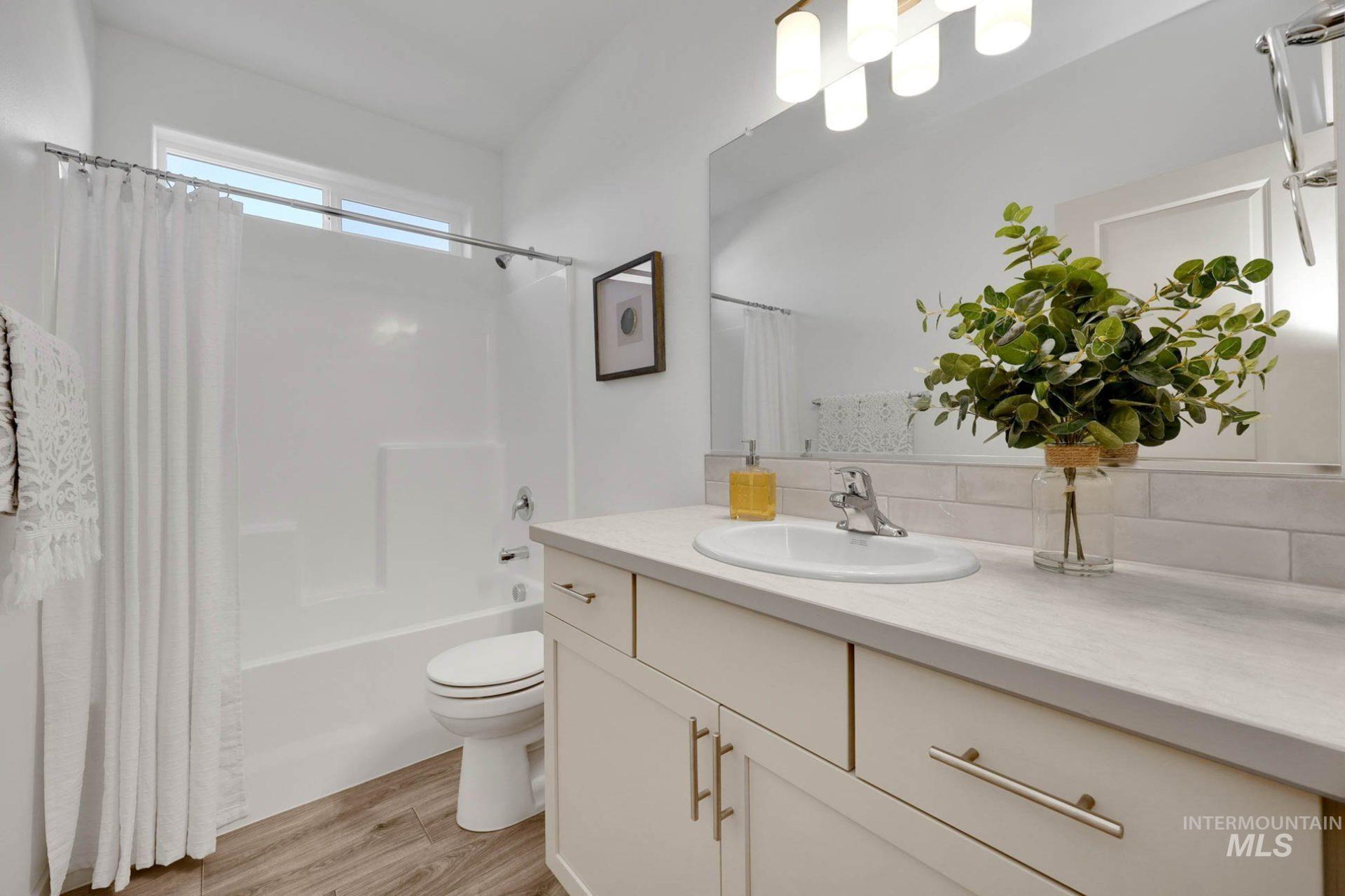 Bathroom with shower / bath combo with shower curtain, vanity, and light wood-style flooring