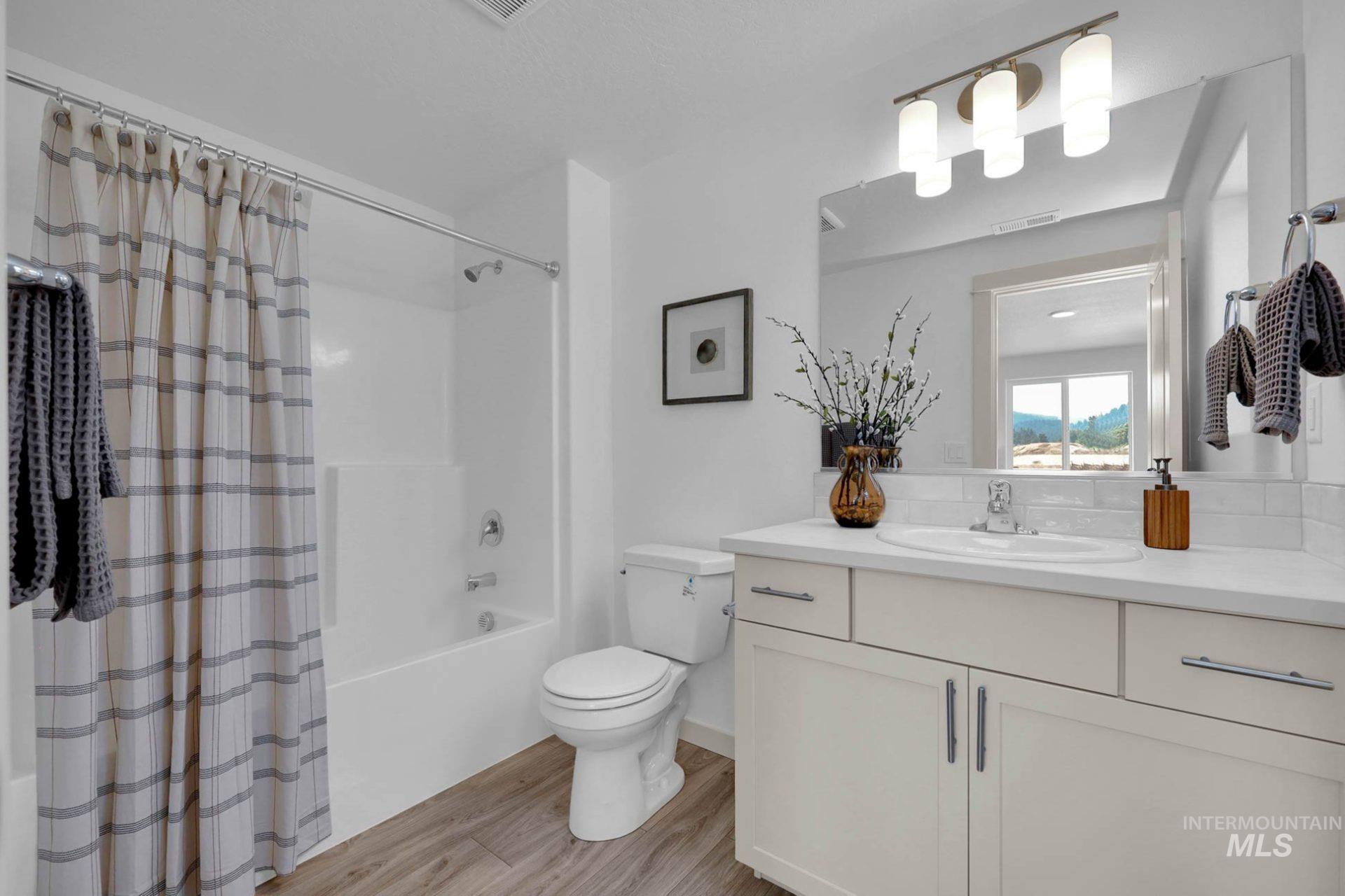 Bathroom featuring shower / tub combo with curtain, vanity, and light wood-type flooring