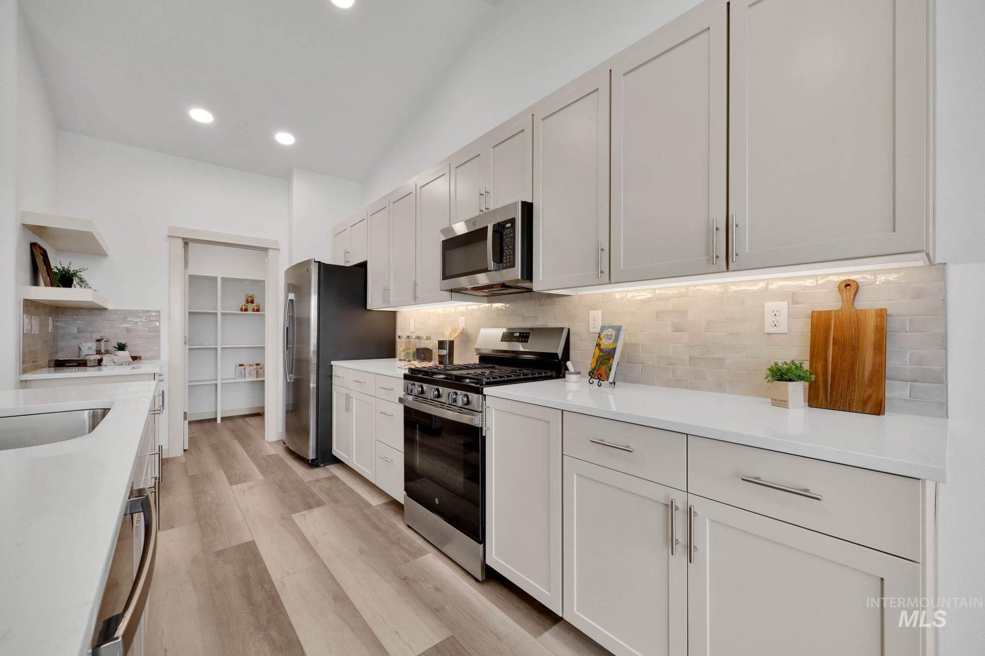Kitchen featuring tasteful backsplash, appliances with stainless steel finishes, light stone countertops, light wood-style flooring, and recessed lighting