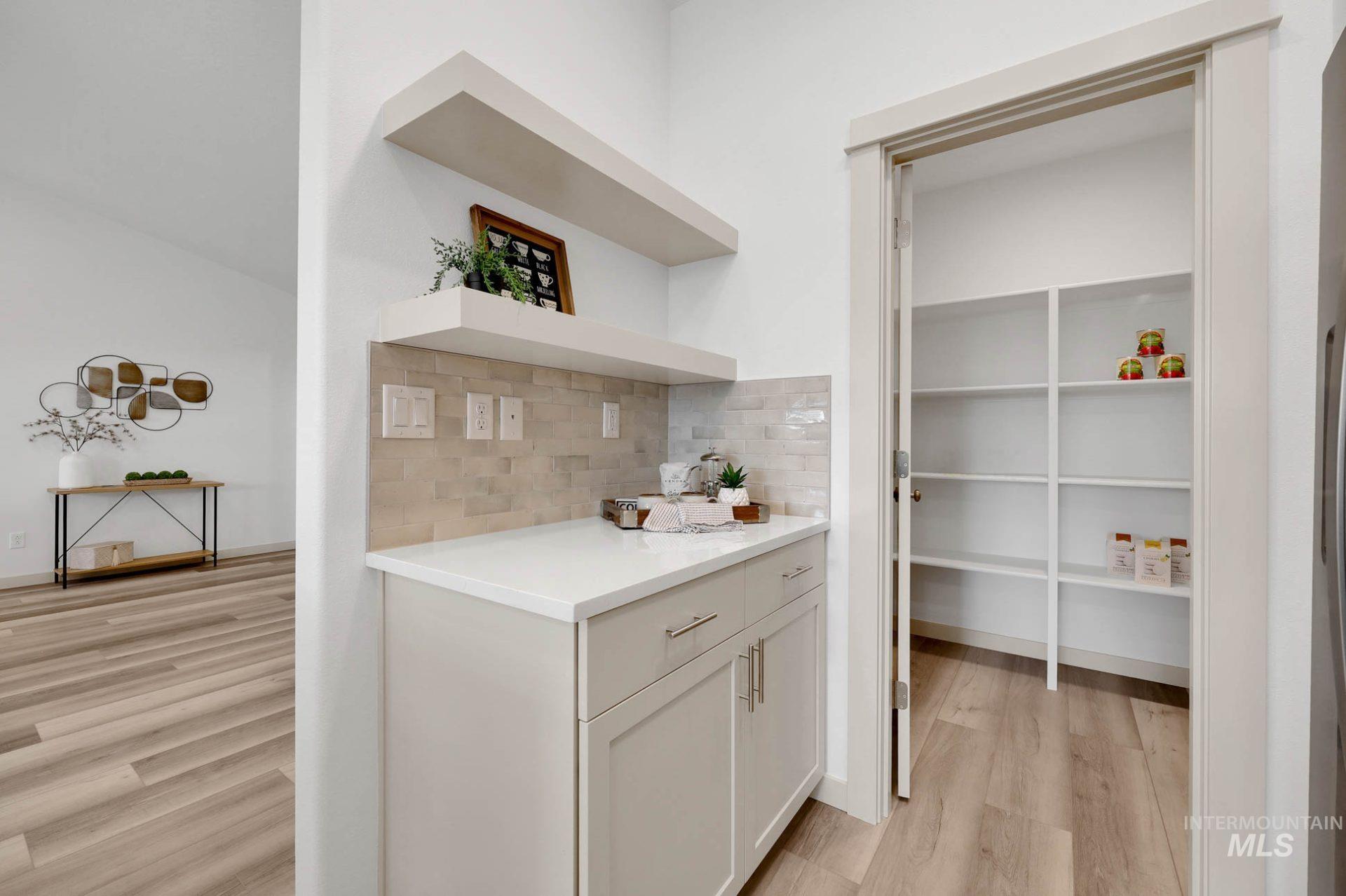 Bar featuring light wood finished floors, open shelves, backsplash, and white cabinets