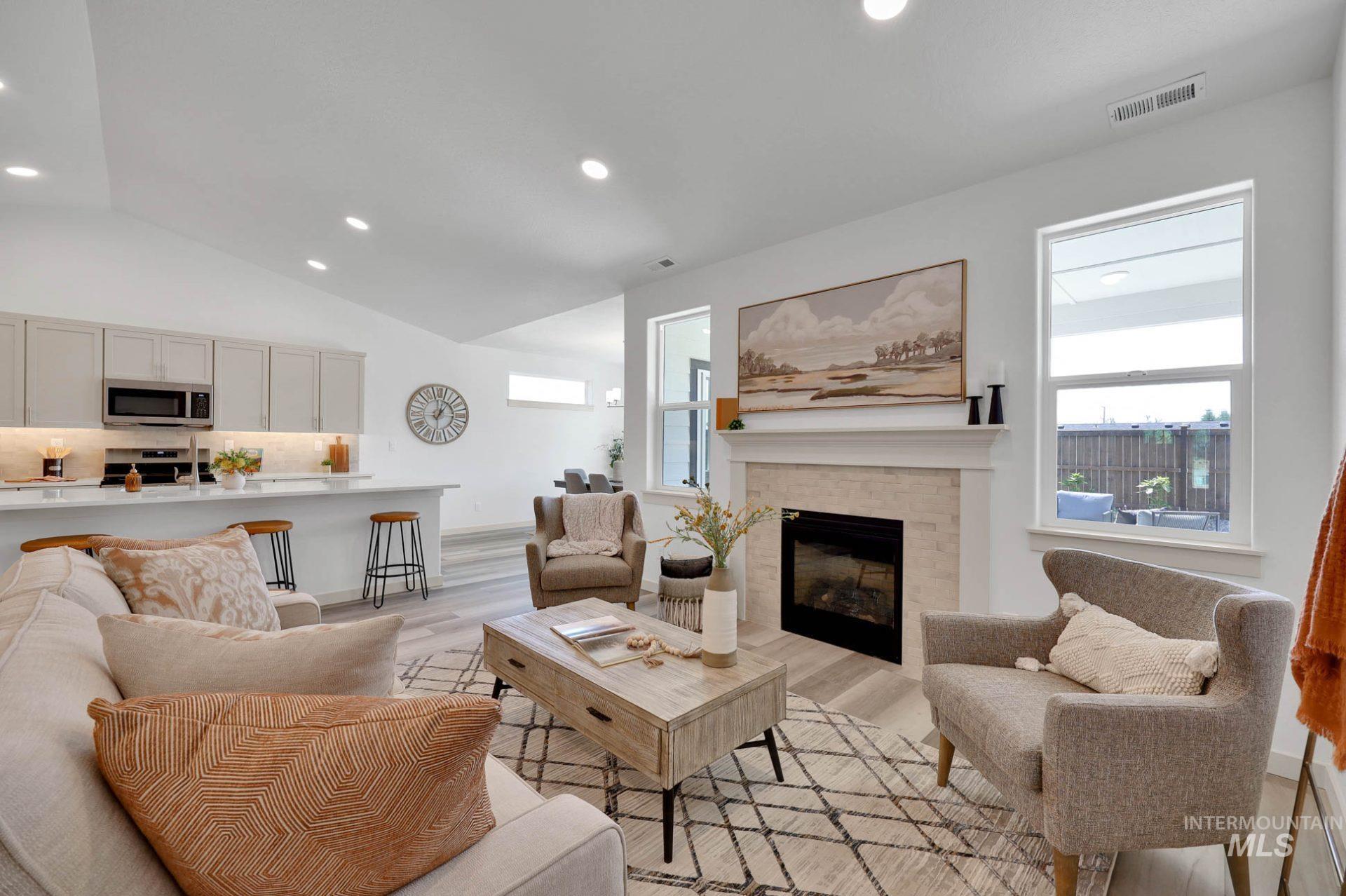 Living room featuring healthy amount of natural light, recessed lighting, a fireplace, light wood-style floors, and vaulted ceiling