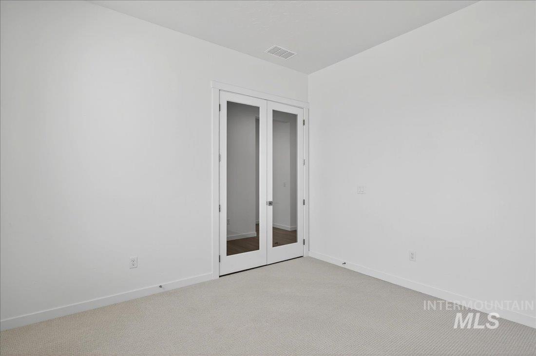 Unfurnished bedroom featuring french doors and carpet floors