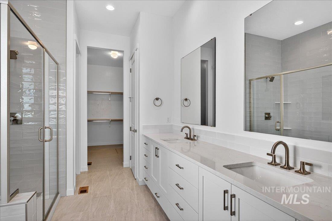 Bathroom featuring double vanity, a stall shower, a walk in closet, recessed lighting, and light tile patterned floors