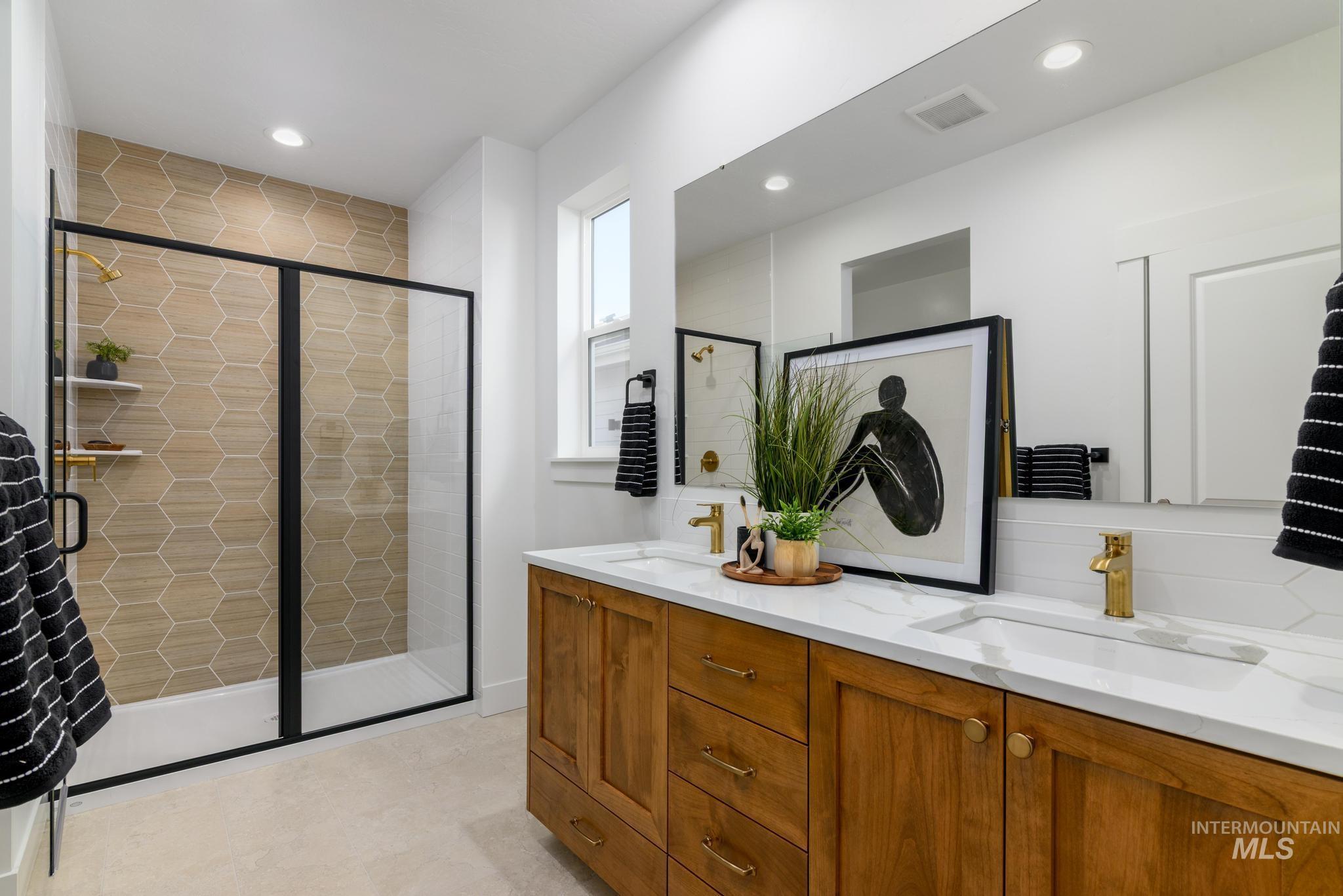 Full bathroom with double vanity, a stall shower, and recessed lighting