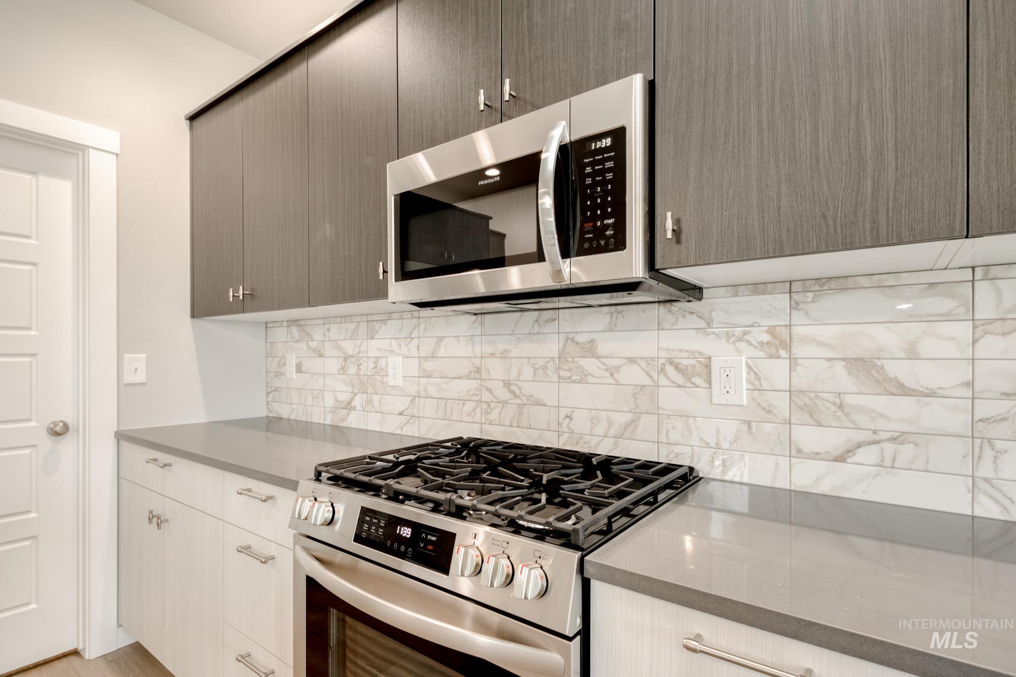 Kitchen featuring stainless steel appliances, tasteful backsplash, dark stone counters, and modern cabinets