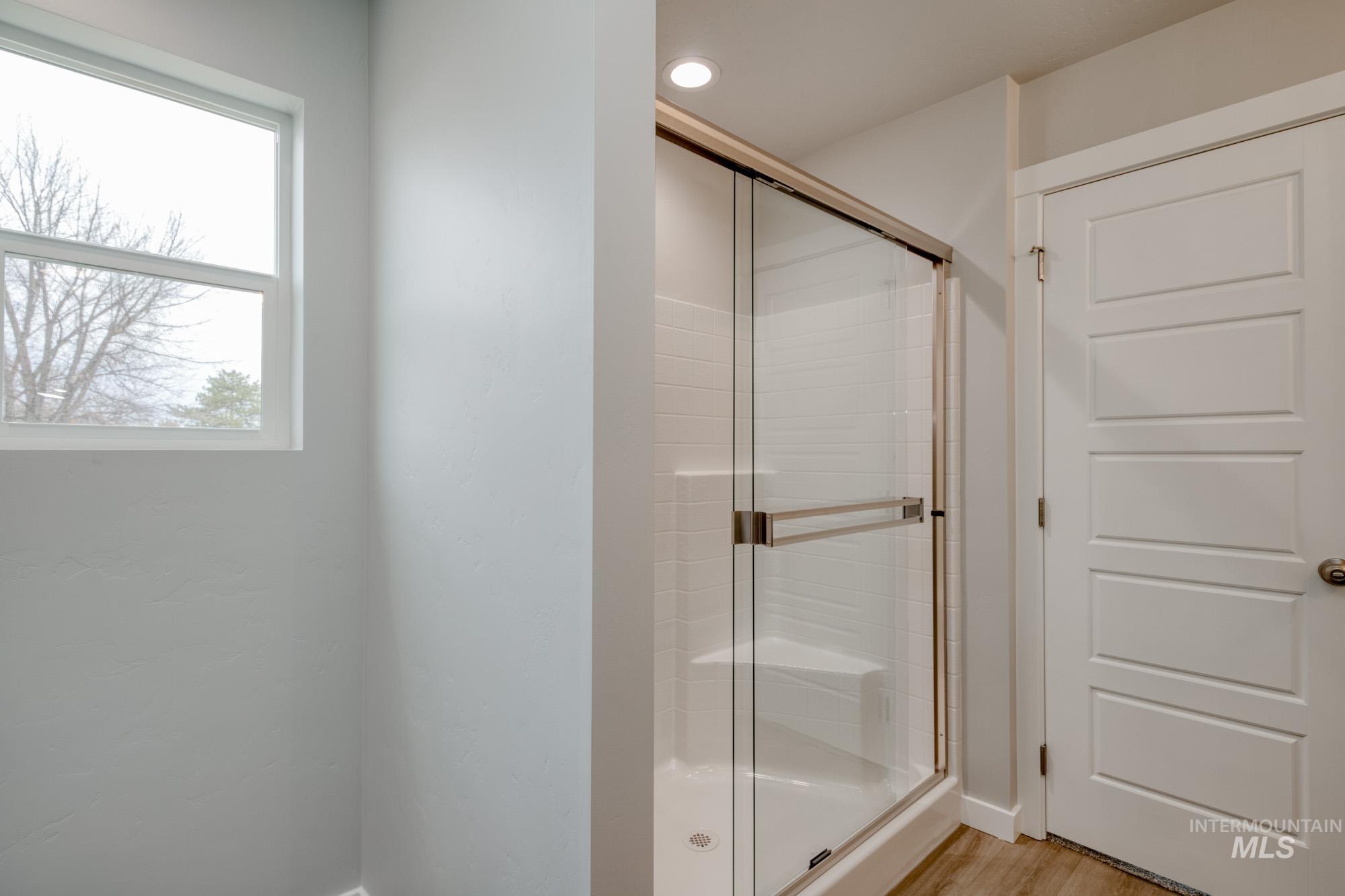 Full bath with a stall shower, light wood-type flooring, and recessed lighting