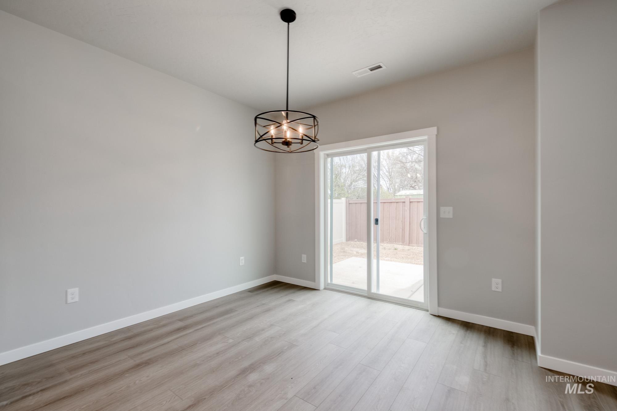 Empty room featuring light wood-style floors and a chandelier