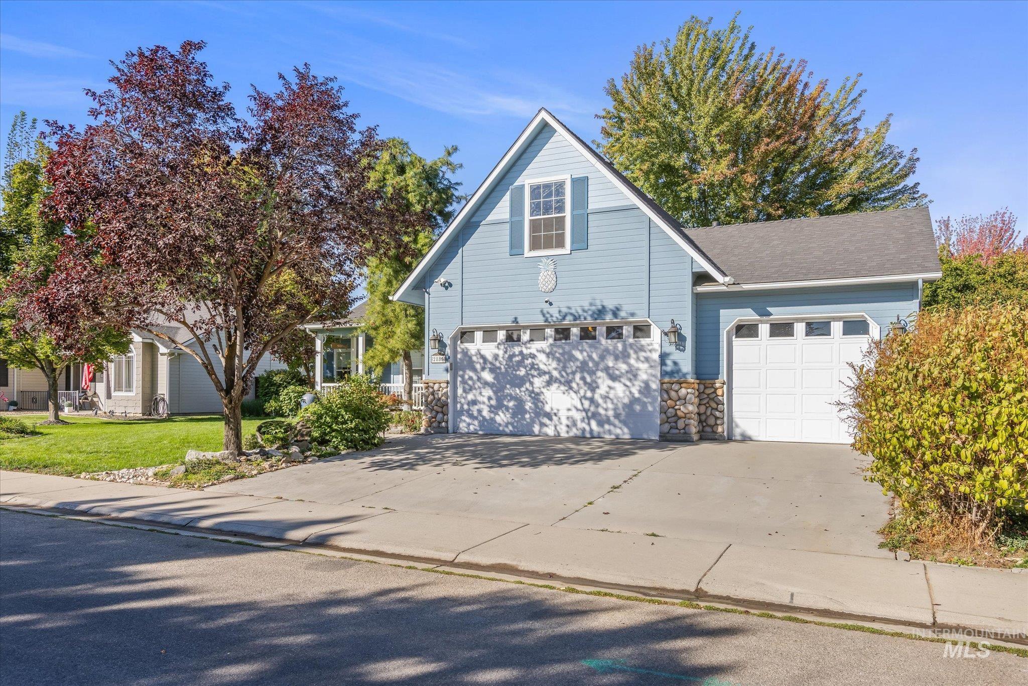 Traditional-style house with concrete driveway, stone siding, and a front yard