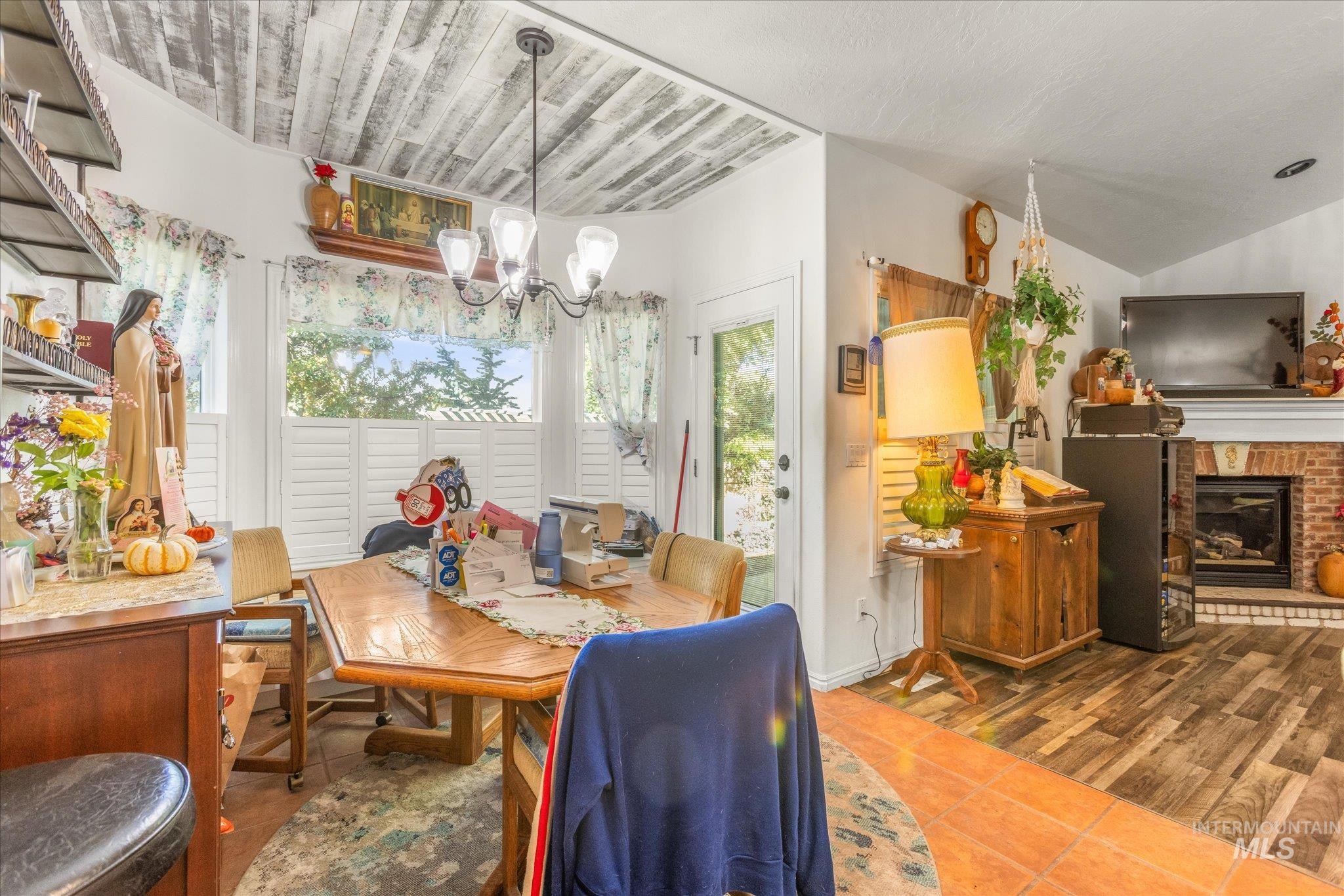 Dining space featuring dark tile patterned flooring, a fireplace, and a chandelier